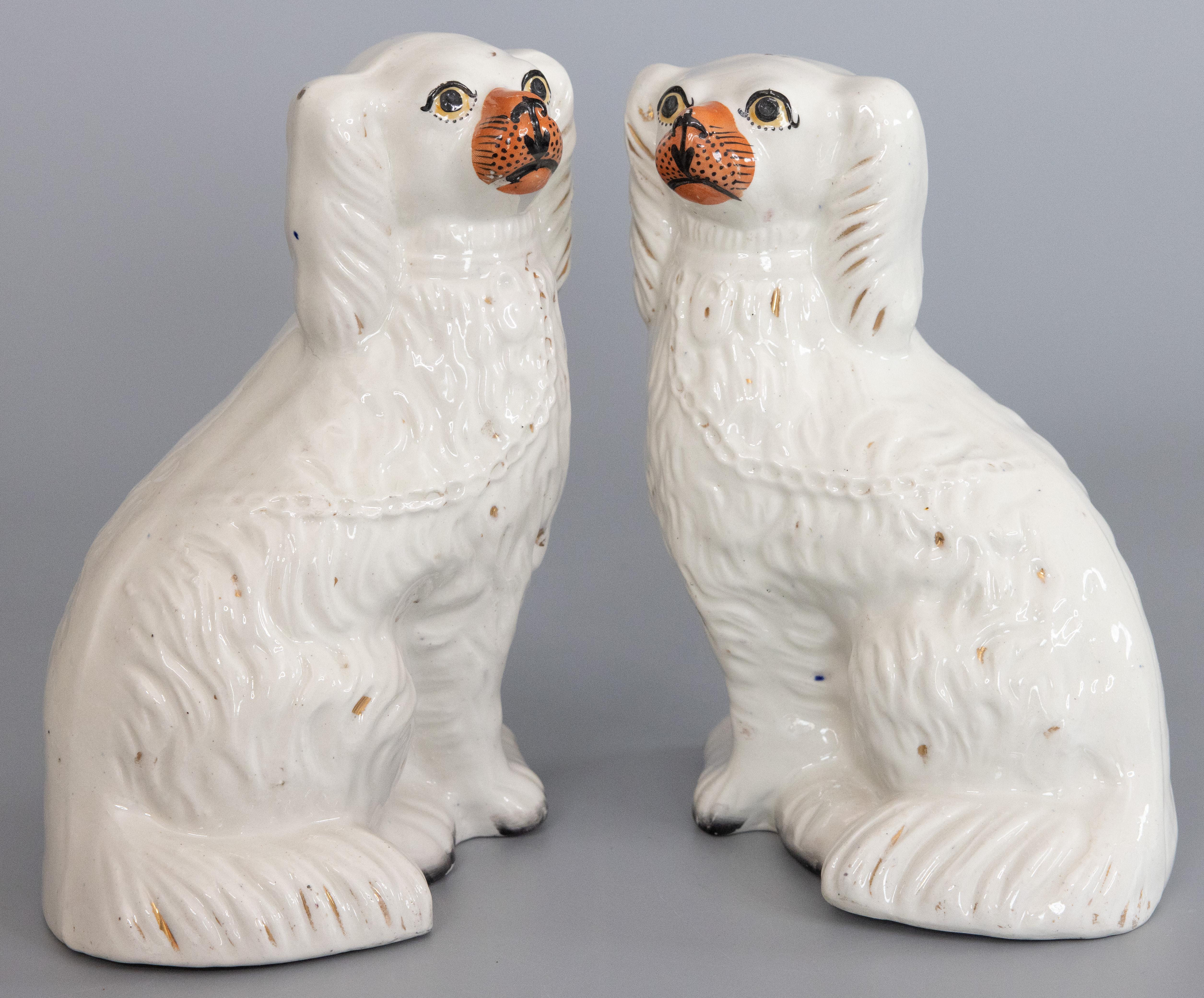 A fine pair of antique 19th-Century English Staffordshire mantel dogs. These charming dogs are hand painted with lovely gilt details and sweet faces. They are the perfect Victorian pair of dogs for your mantel, bookcase, or table.
