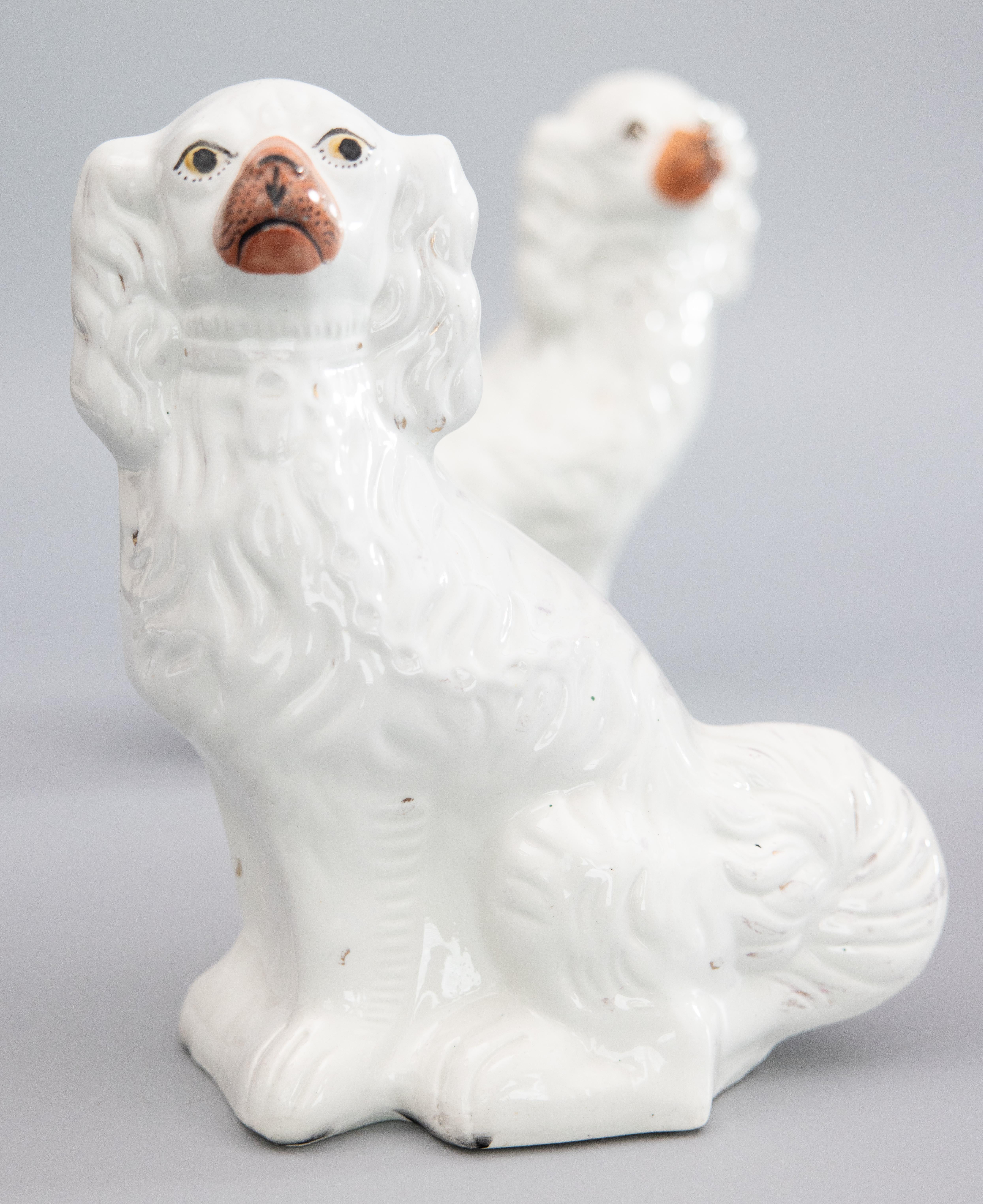 A fine pair of antique 19th-Century English Staffordshire white spaniel dog figurines. These charming dogs are a nice large size, hand painted with lovely details and sweet faces. They are the perfect Victorian pair of dogs for your mantel,