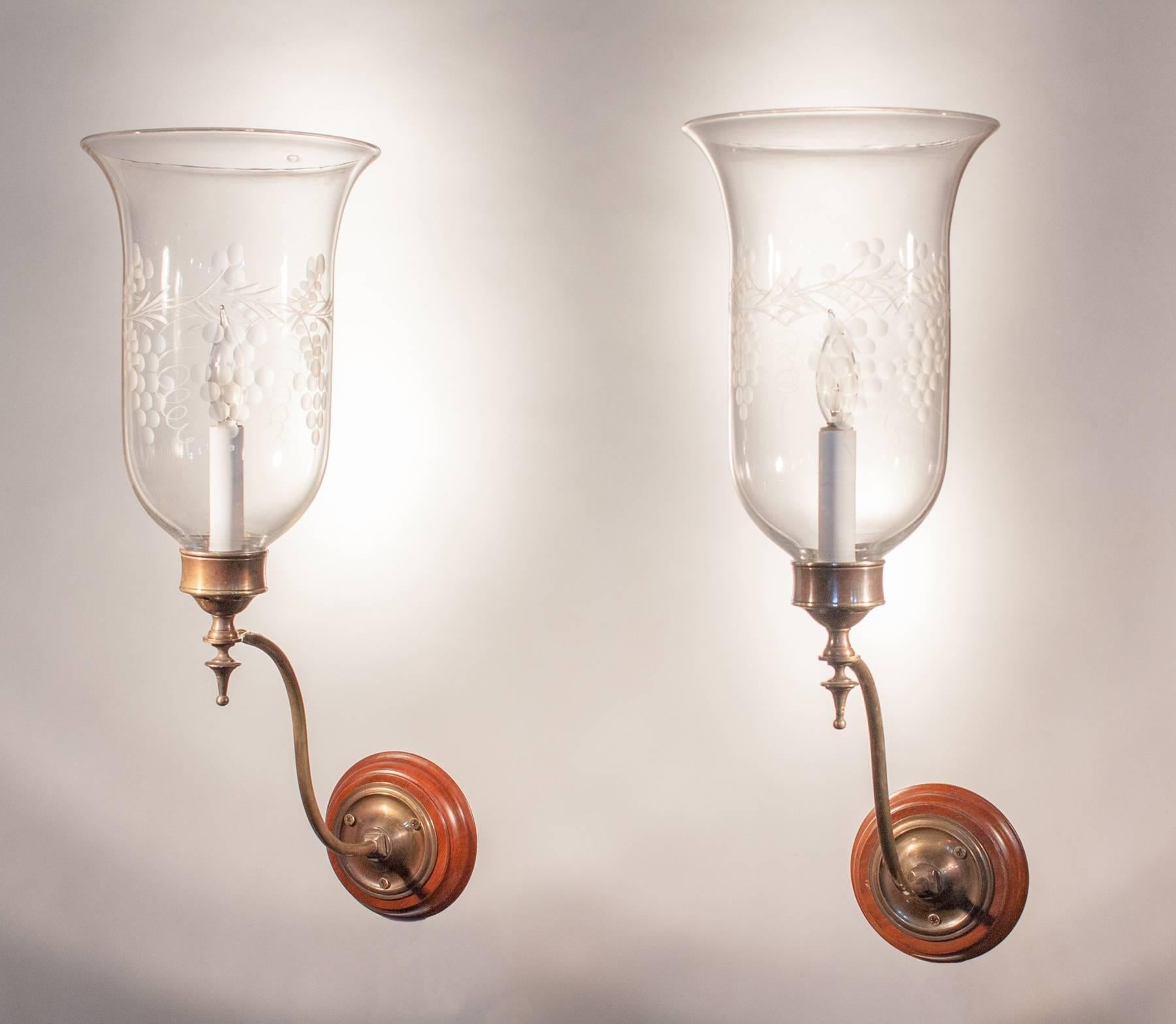 An exceptional pair of antique English hurricane sconce shades. These circa 1890 handblown glass shades feature an etched grape and vine motif that complements the flared form. The wall sconces have been newly electrified, each with a single