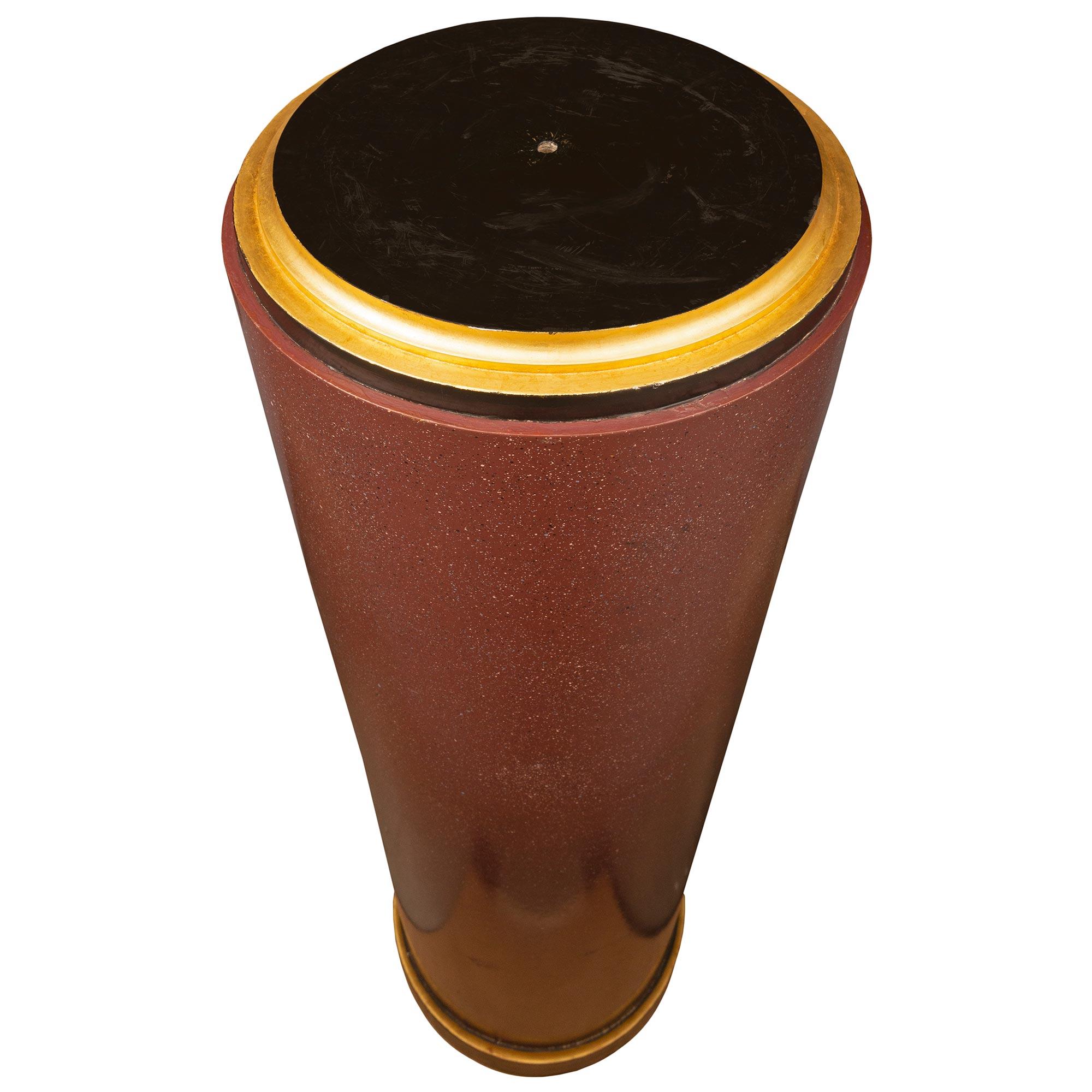An impressive and large scale pair of 19th century faux painted porphyry, ebony and giltwood pedestal columns. Each pedestal is raised by a fine circular ebony base with a most elegant wrap around giltwood band. The circular central supports display
