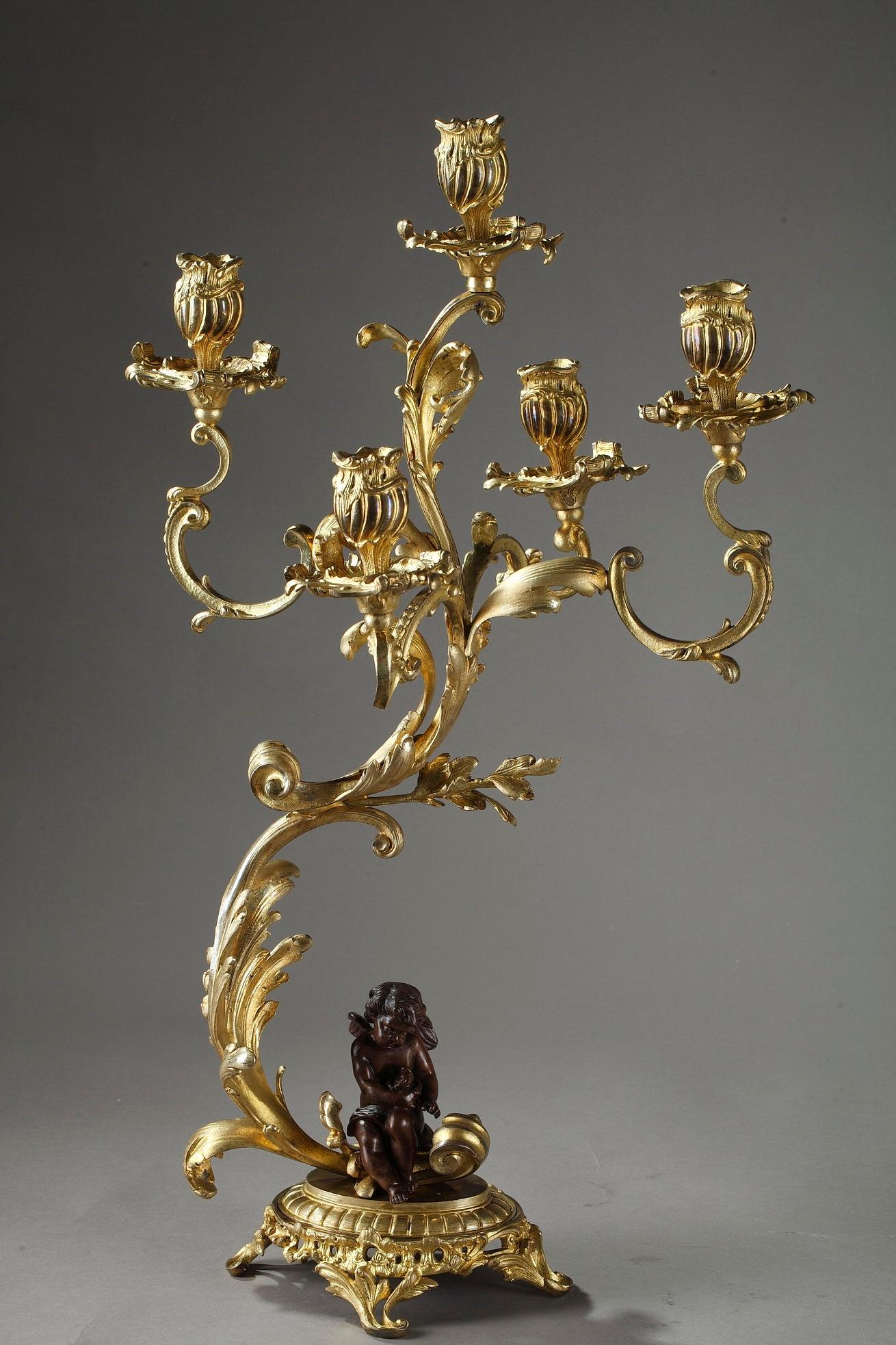 A set of gilt and patinated bronze candelabra lamps, each with five branches intricately decorated with rinceau and scrolling foliages. Influenced by Louis XV style, with its flowing lines and graceful form that are rendered in sumptuous detail.