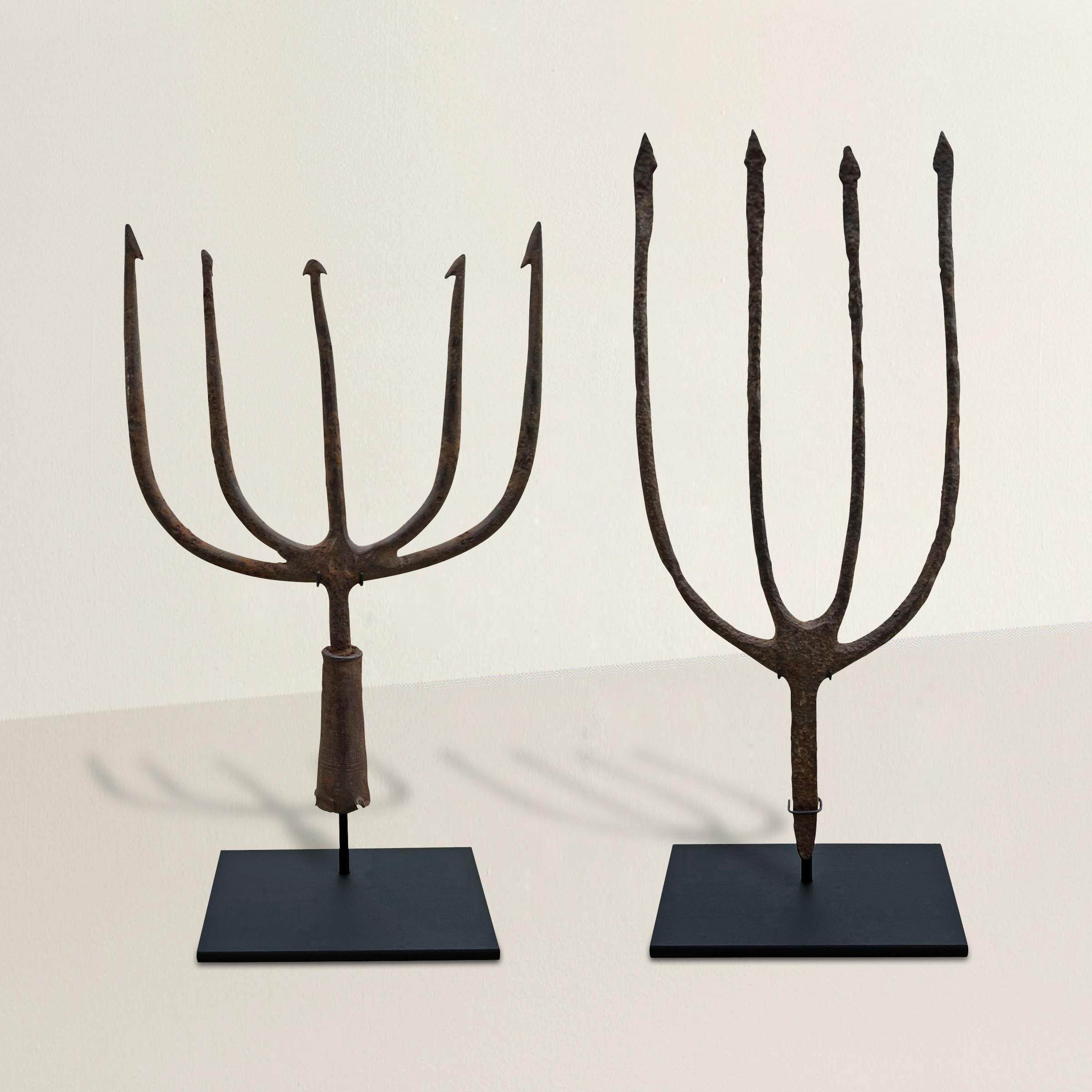 A hardworking and loyal pair of 19th century American hand-wrought iron fishing spears with arrow points, and mounted on custom steel stands. Decorate the shelves of your country house, or give the perfect gift to the outdoors sportsperson in your