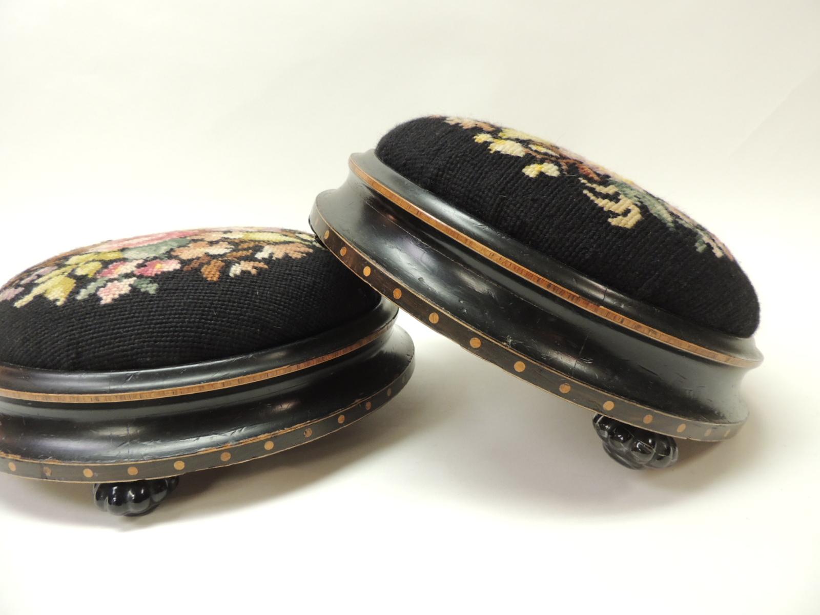 Pair of 19th century English round foot stools
Round foot stools upholstered in a black floral tapestry. The ebonized wood base has inlaid all around.
Black glass feet in the shape of a flower
Size: 12 D x 4.5 H.
 