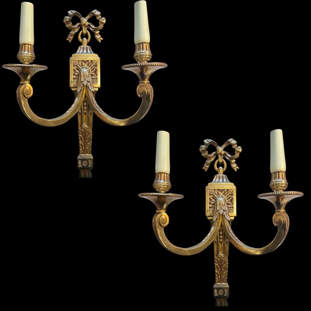 A Pair of 19th Century French Antique Regency Wall Lights, exquisite additions to elevate your space. Crafted from solid brass, these wall lights boast a regal aura with a beautiful ribbon crowning their summits.

The intricate hand-carved floral