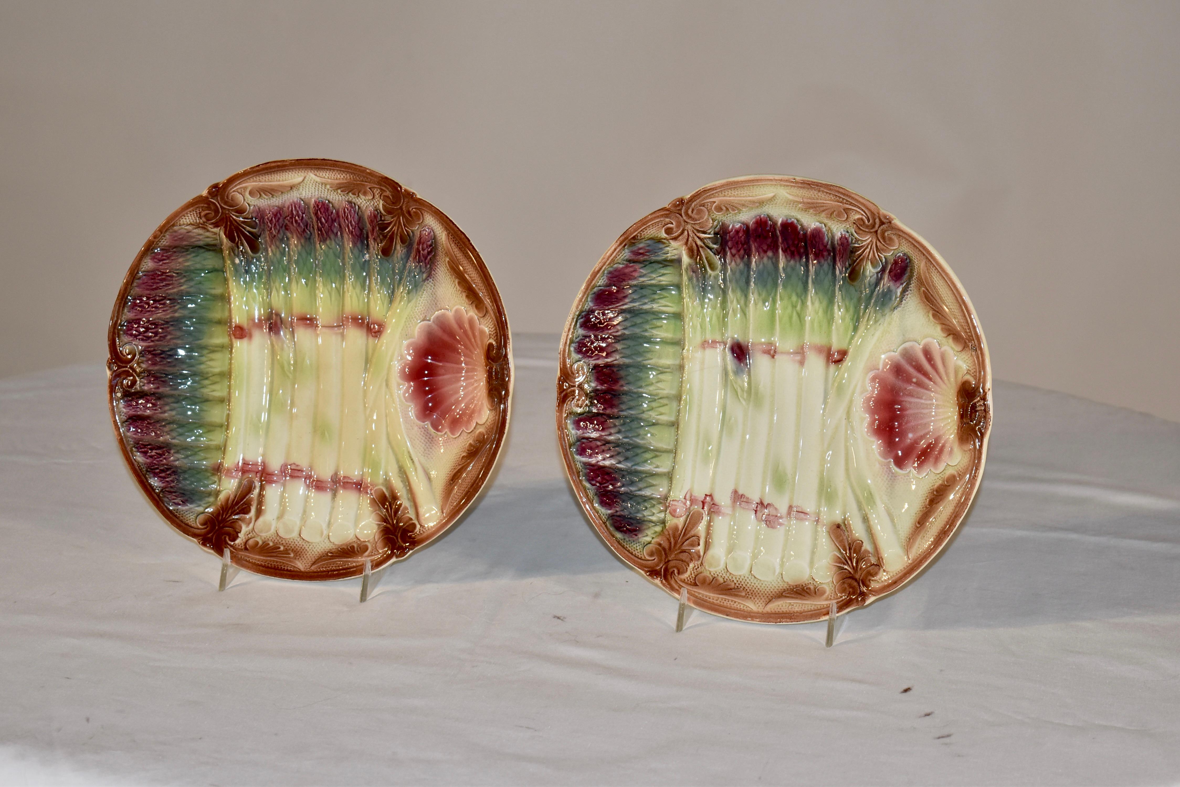 Pair of gorgeous 19th century majolica asparagus plates from France. they have lovely scrolled borders in shades of brown , with crossed asparagus spears in extraordinary detail and color, with a scallop shell shaped indentation to be used for sauce.