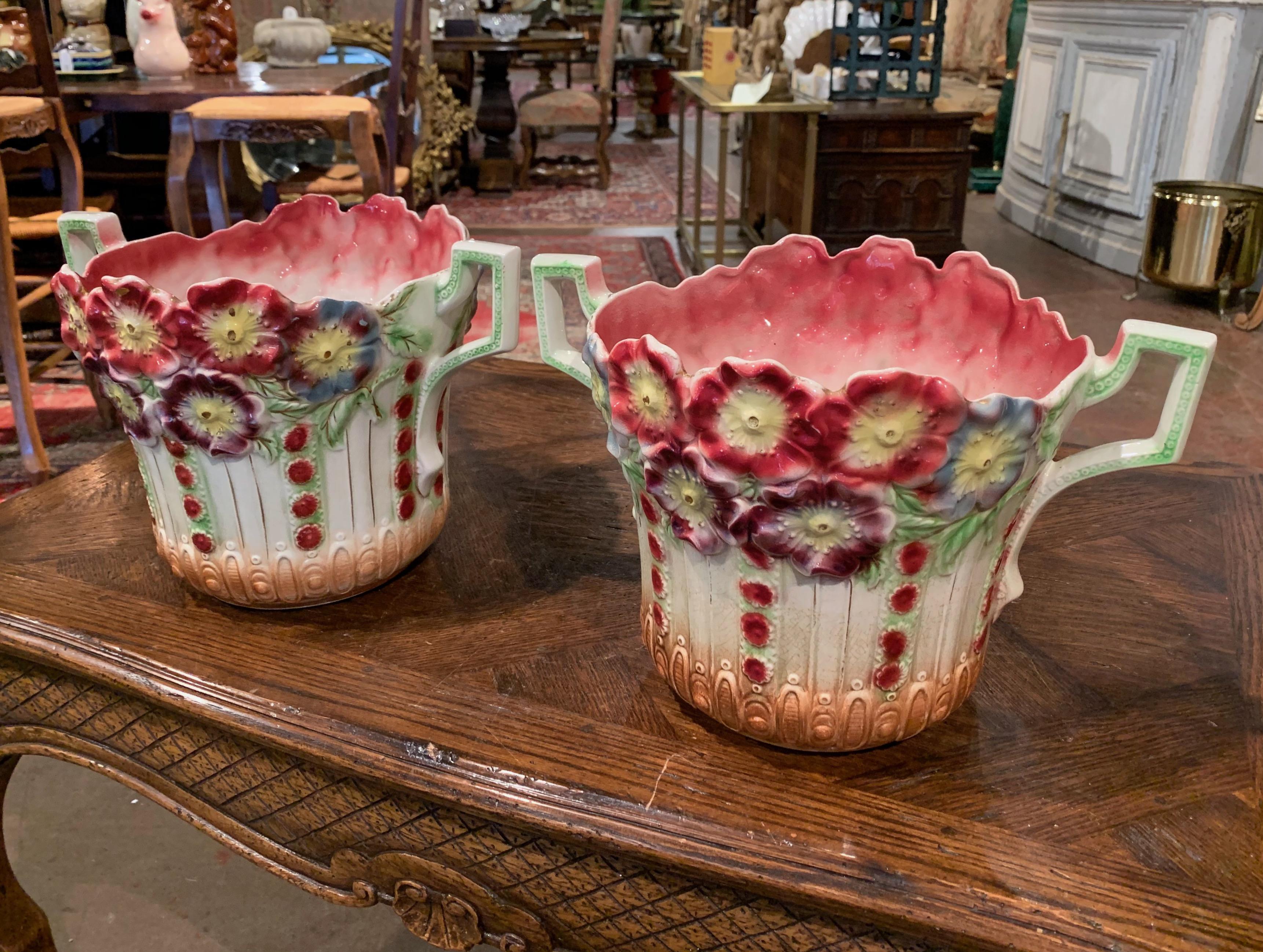 Decorate your mantel with this nice pair of colorful Majolica planters from Onnaing. Created in France, circa 1880, each antique vase is round in shape with scalloped rim, handles on the sides, and features hand painted floral and leaf motifs in the