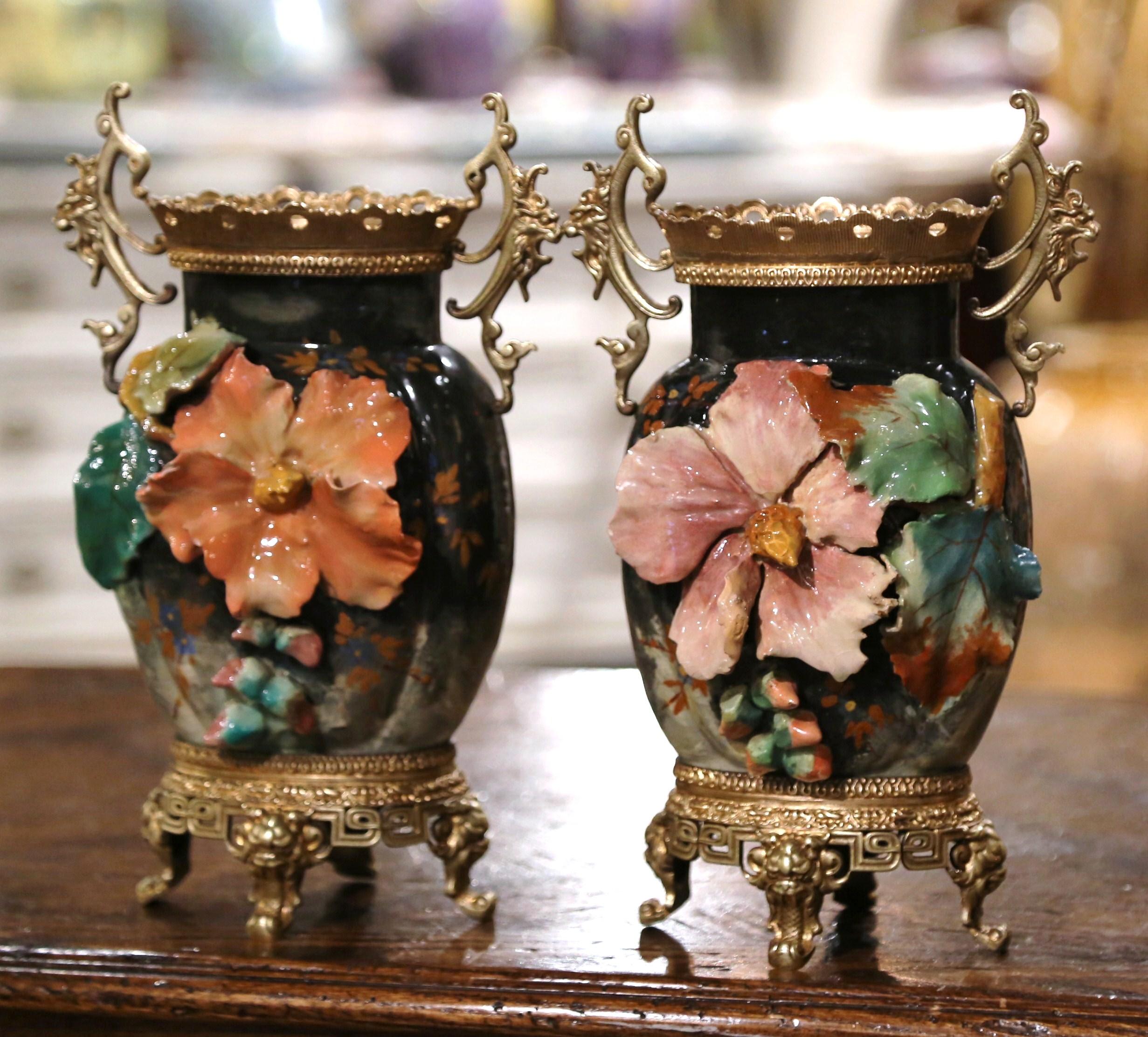 Decorate a kitchen counter or a shelf with this elegant pair of antique Majolica vases. Crafted in Montigny sur Loing, France, circa 1860, each ornate vase sits on an ornate brass base ending with mask scrolled feet; it is further decorated at the