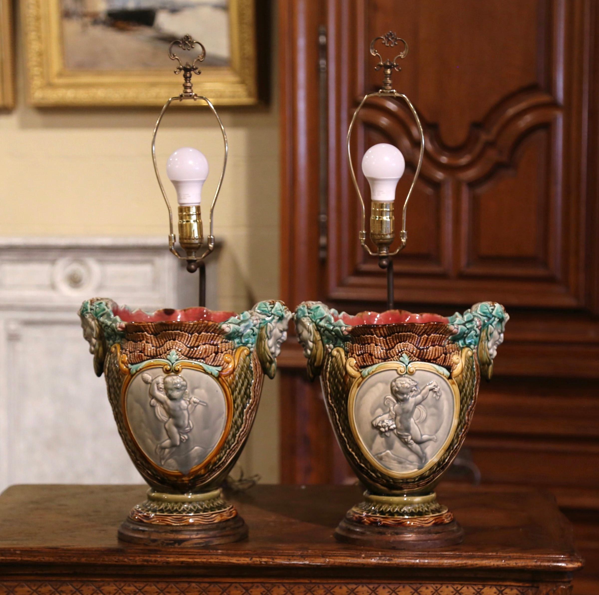 Bring a little Neoclassical French flair into your home with this colorful pair of vases converted into table lamps. Crafted in France, the handcrafted Majolica cachepots are dressed with Bacchus figure handles in high relief; they are further