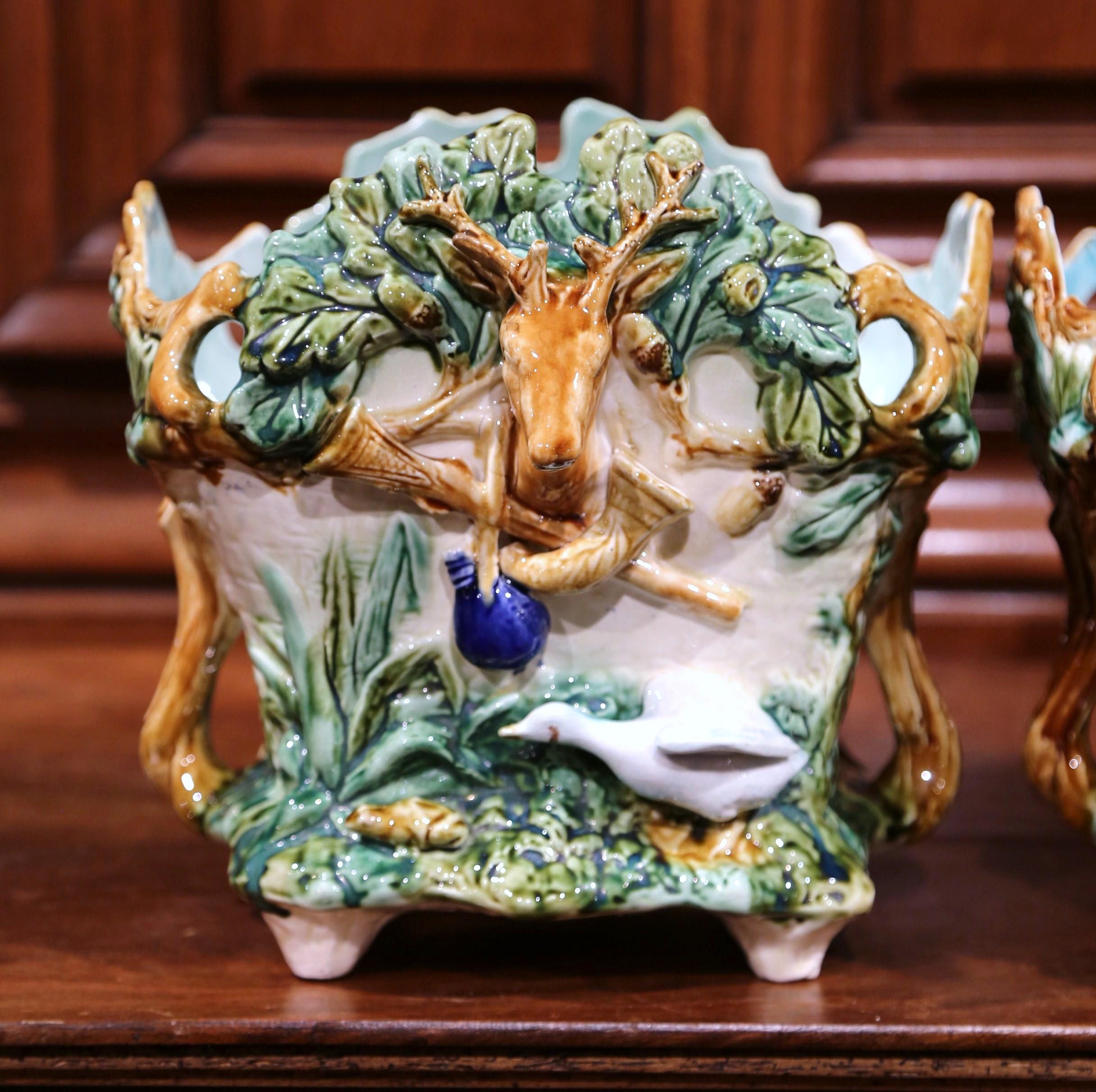 Decorate a ranch or hunting lodge with these colorful majolica jardinières. Created in France by L'Hermine a Orchies, circa 1880, and almost square in shape, each antique porcelain cache pot features exquisitely rendered hunting motifs on all four