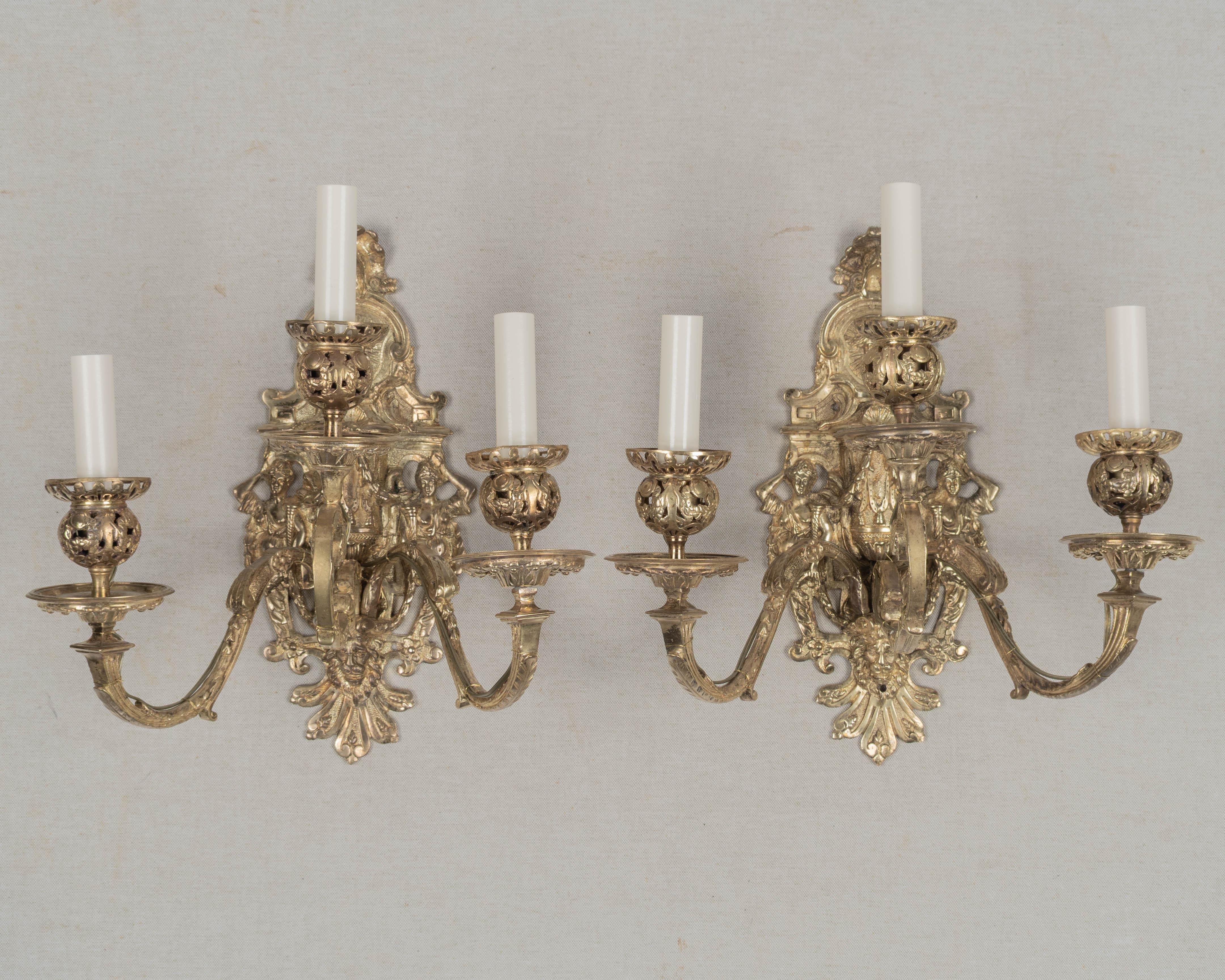 Coppia di applique a tre luci in bronzo fuso in stile barocco francese del XIX secolo. Applique pesanti, ornate di dettagli con bracci a voluta e coppe per candele forate. Piastra posteriore finemente fusa con coppie di cariatidi, ghirlande