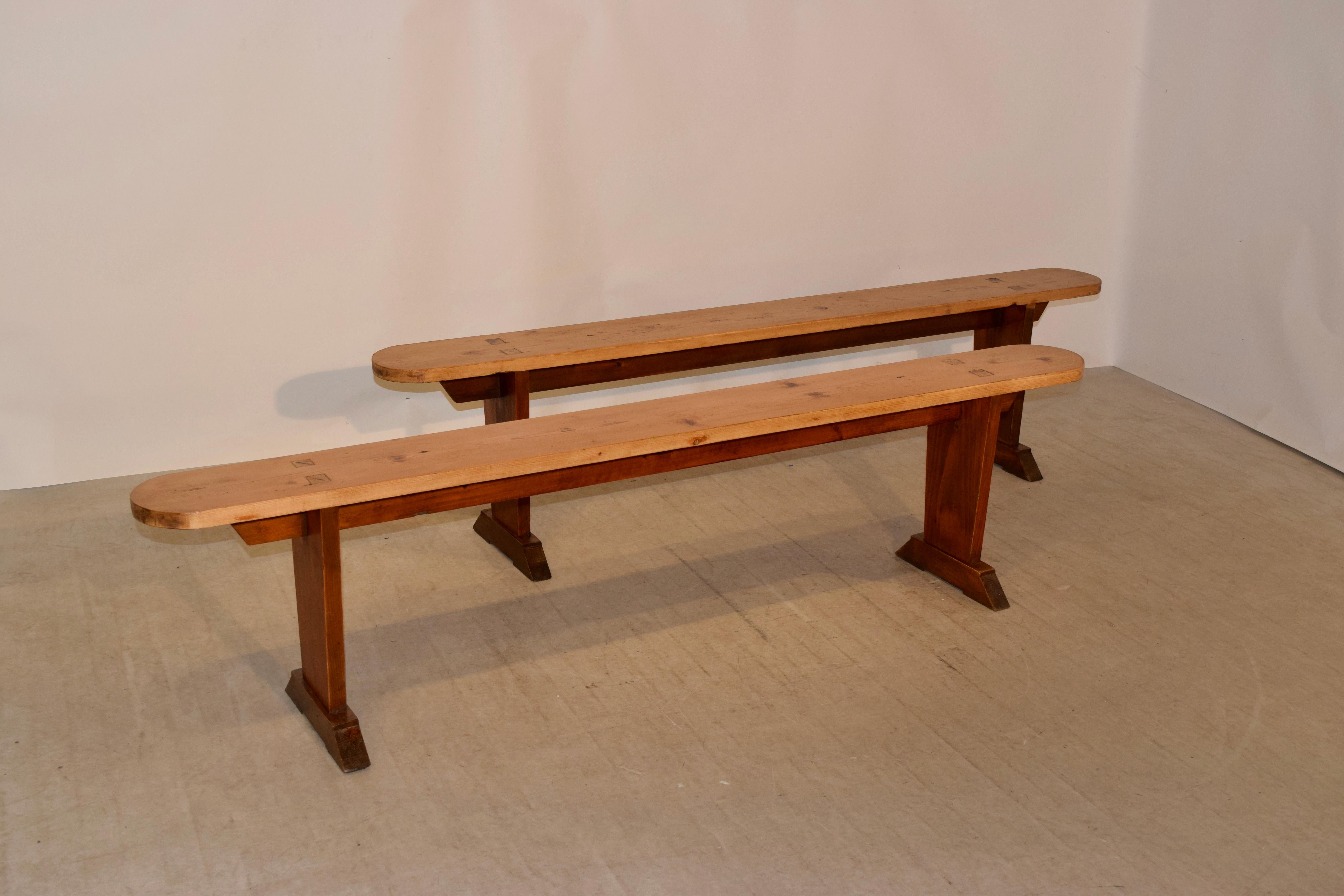 Pair of 19th century pine benches from France with plank seats with rounded ends and pegged construction following down to simple bases with tapered vase type legs.