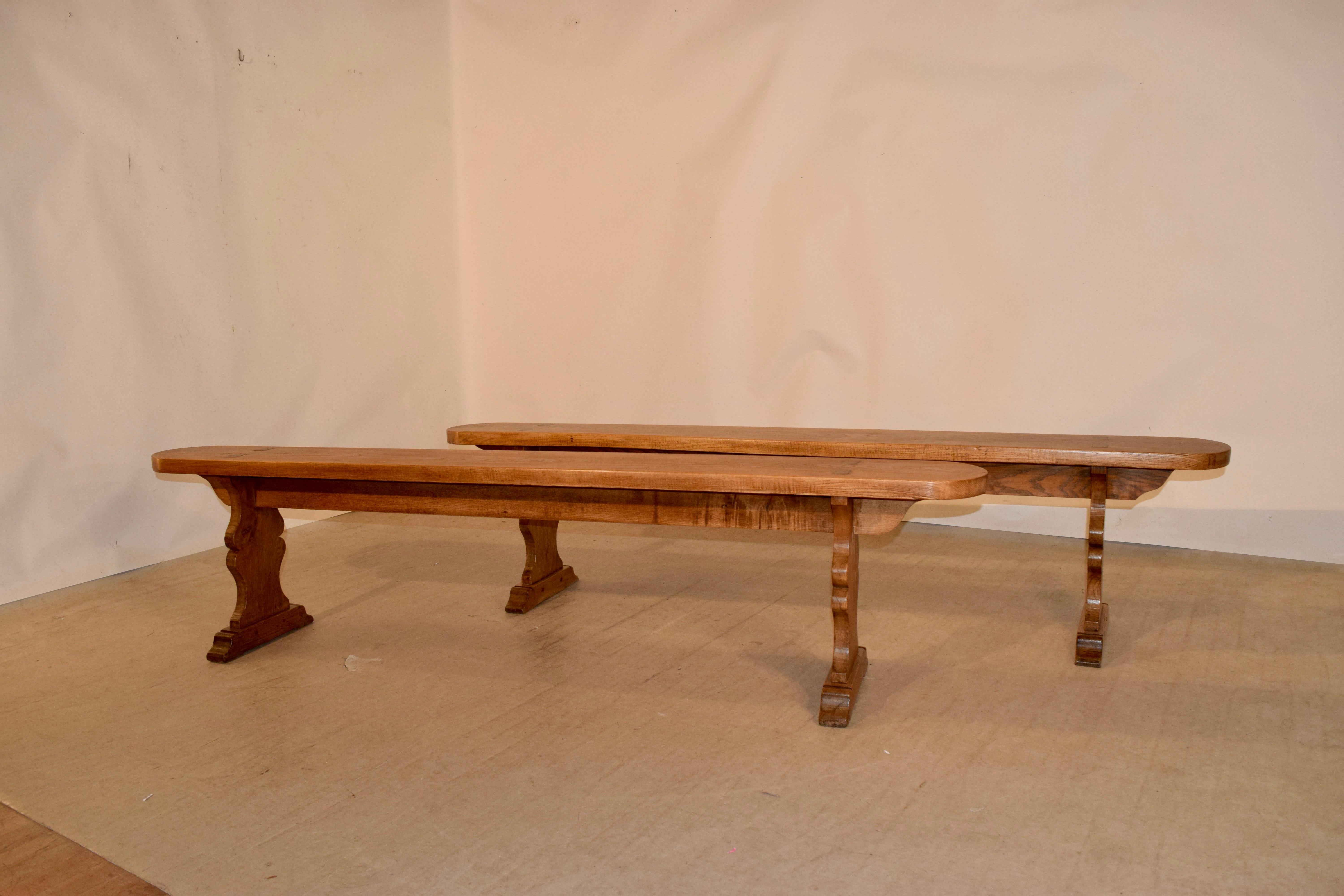 Pair of 19th century elm benches from France with rounded ends and vase shaped pedestal legs, ending in hand shaped feet. The seats measure 8.88 in depth.