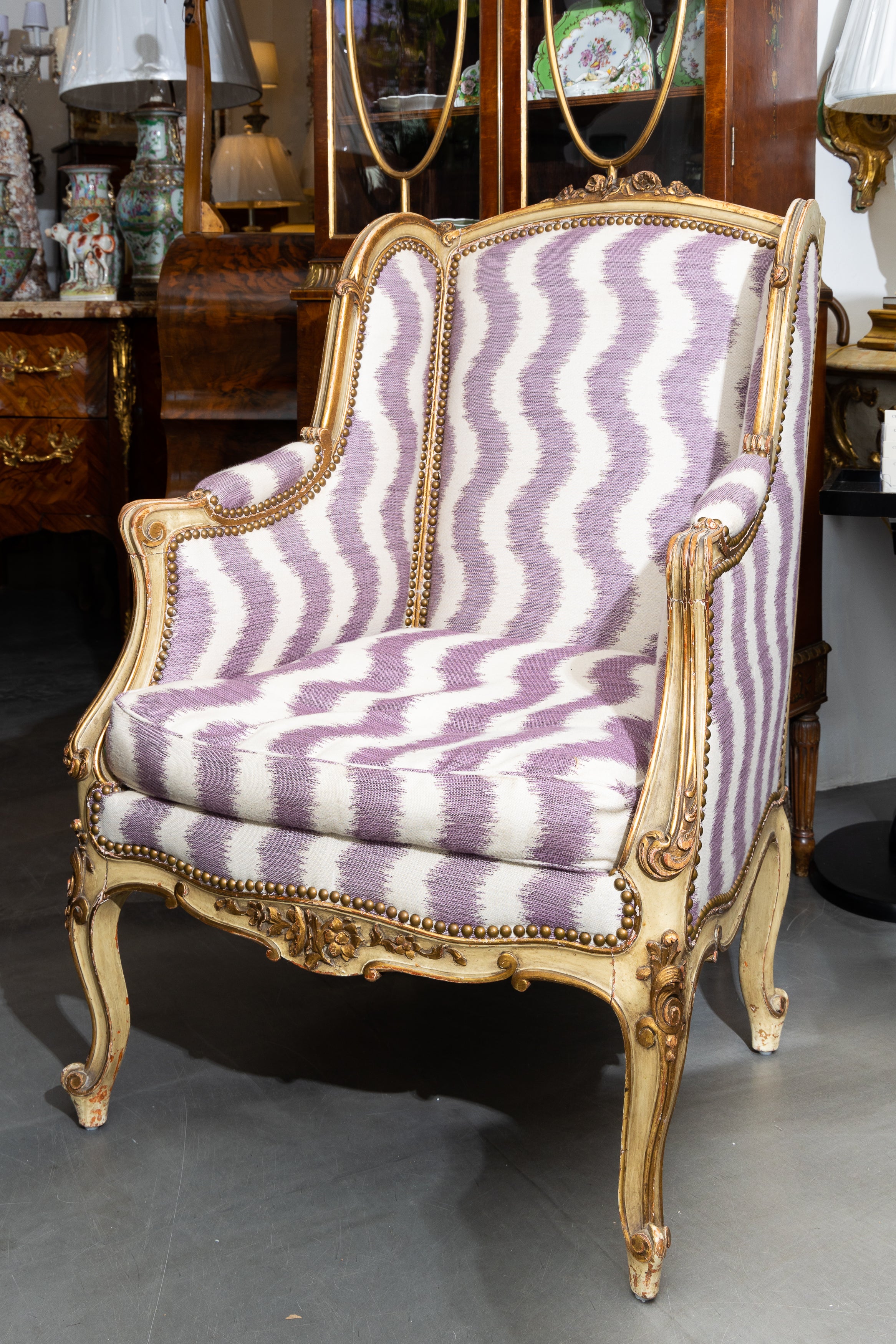 This is a pair of painted and parcel gilt French Louis XV style wing back bergeres, upholstered in a quirky contemporary lavender and white curvy stripe, 19th century.