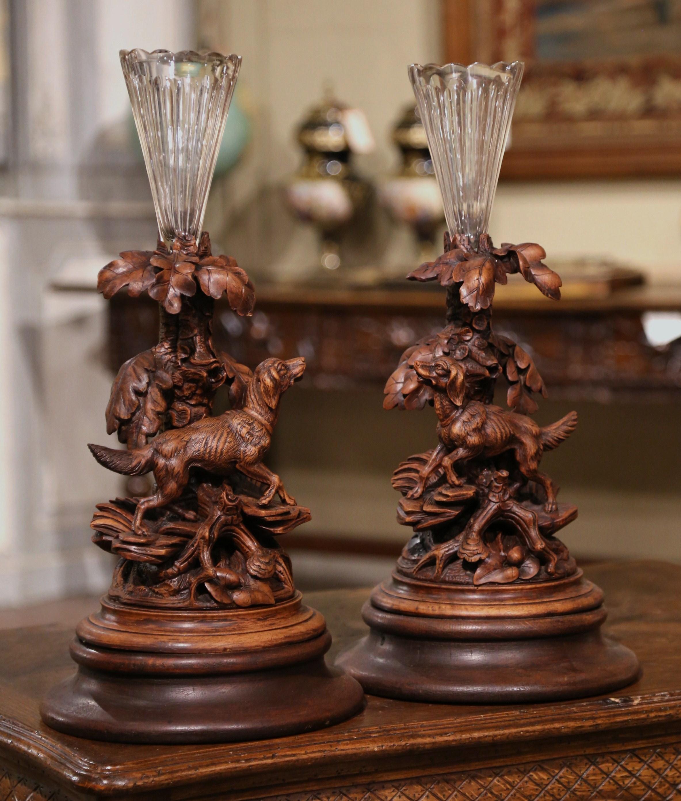 Decorate a mantel or a man's office with this elegant pair of antique Black Forest carvings with matching vases. Carved in France circa 1870, each large sculpture rests on a circular base and features an hand carved composition with a hunting setter