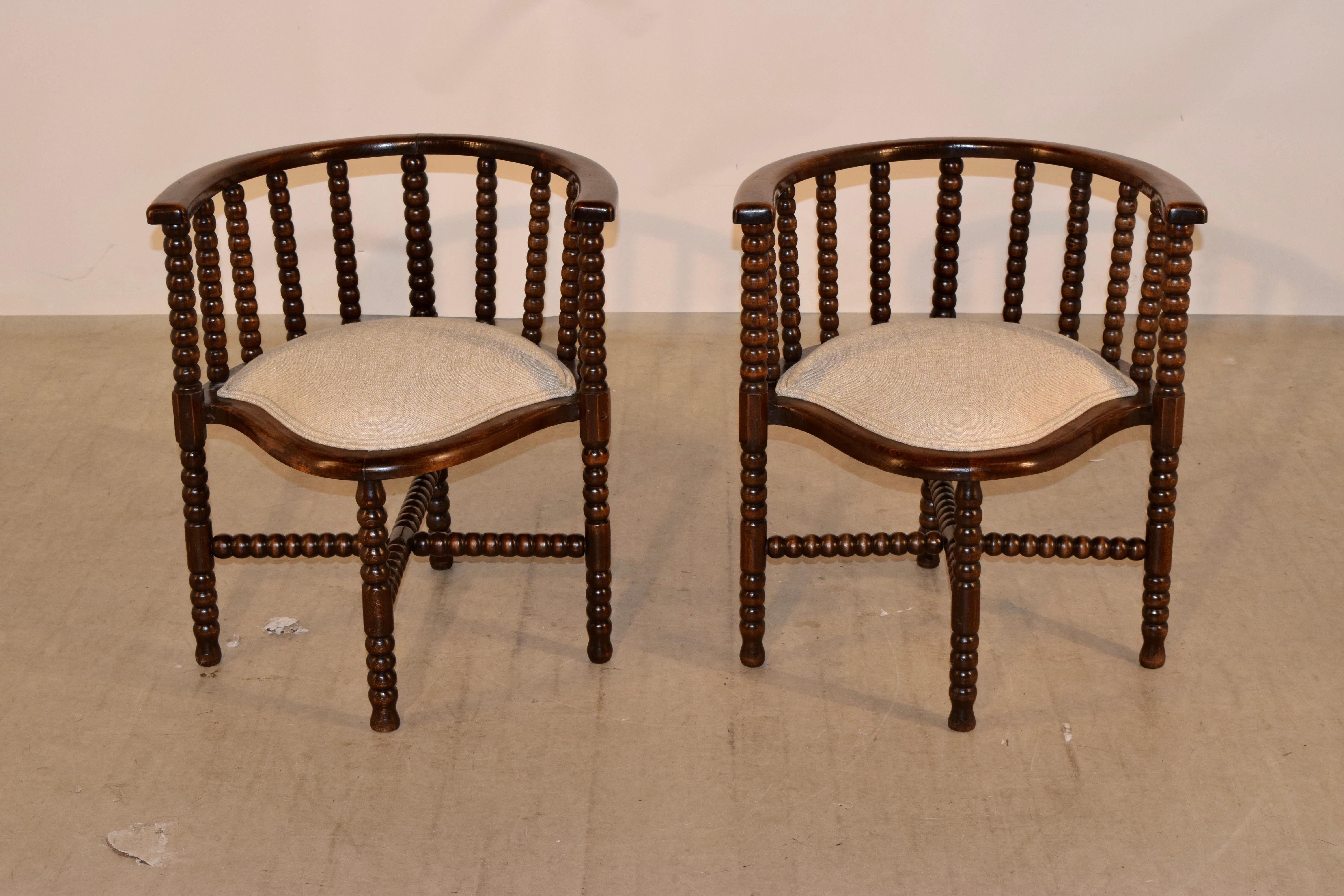 Pair of 19th century oak bobbin chairs from France. They have a wonderfully curved back design and hand-turned bobbin spindles. The seats have lovely scalloped shapes and are newly upholstered in linen. They are finished with a double welt. The legs