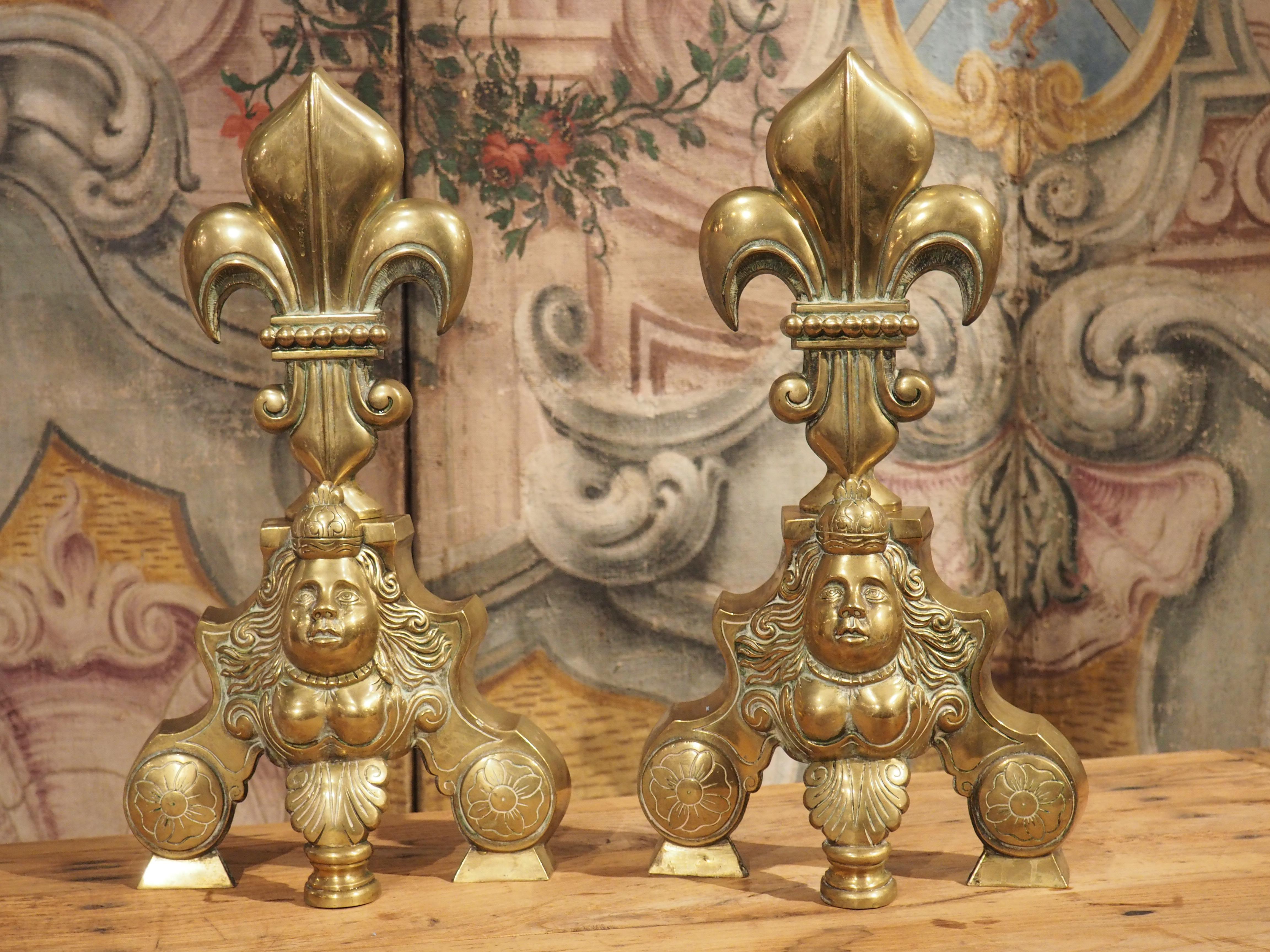 Historically associated with the French monarchy, the fleur de lys is a stylized version of a lily flower. Our pair of French brass fleur de lys chenets, which are from the 1800’s, also feature a crowned mascaron beneath each flower. At only 4 1/2