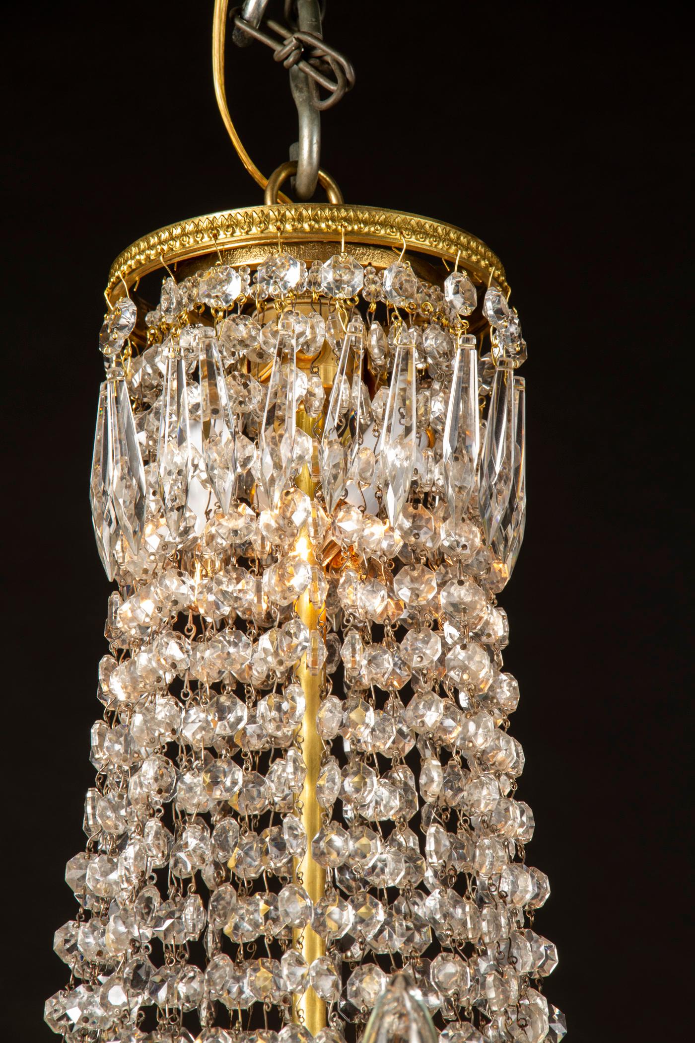 Questa splendida coppia di lampadari francesi del XIX secolo è realizzata in bronzo in stile Impero. In particolare, ognuno di essi è caratterizzato da un piatto centrale in cristallo di immacolata bellezza. La coppia presenta anche bobeches di