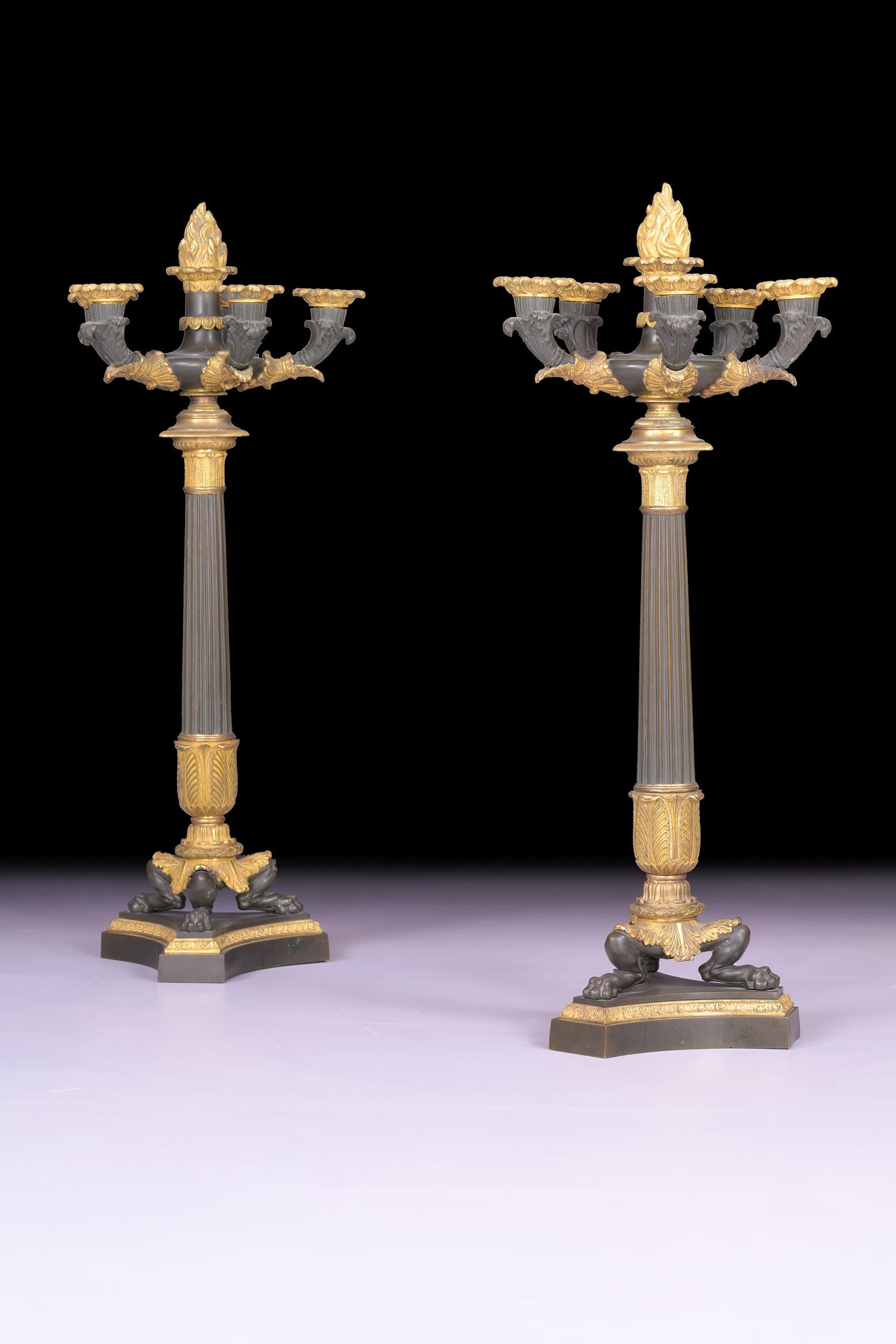 An exceptional pair of early 19th century bronze and ormolu six light candelabra, each with scrolling foliate branches above tapering reeded stems, on beautifully decorated lion's feet with acanthus leaves. resting on triform bases.

Circa