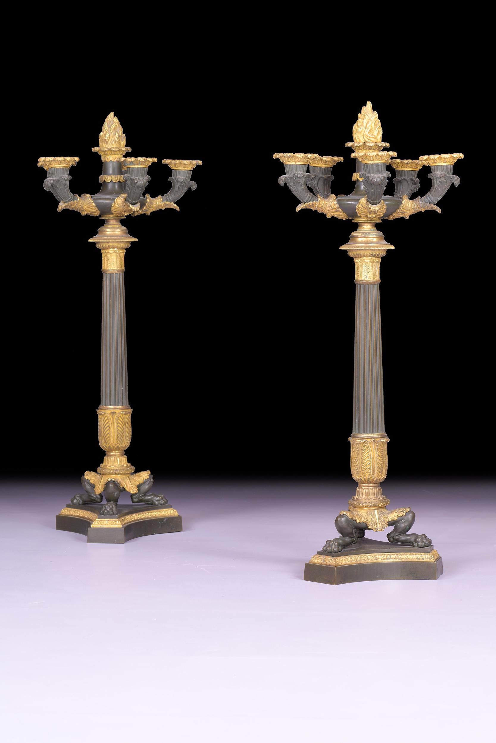 Eccezionale coppia di candelabri a sei luci in bronzo e ormolu dell'inizio del XIX secolo, ognuno dei quali presenta rami fogliacei a spirale che sovrastano steli affusolati e scanalati, su zampe di leone splendidamente decorate con foglie d'acanto