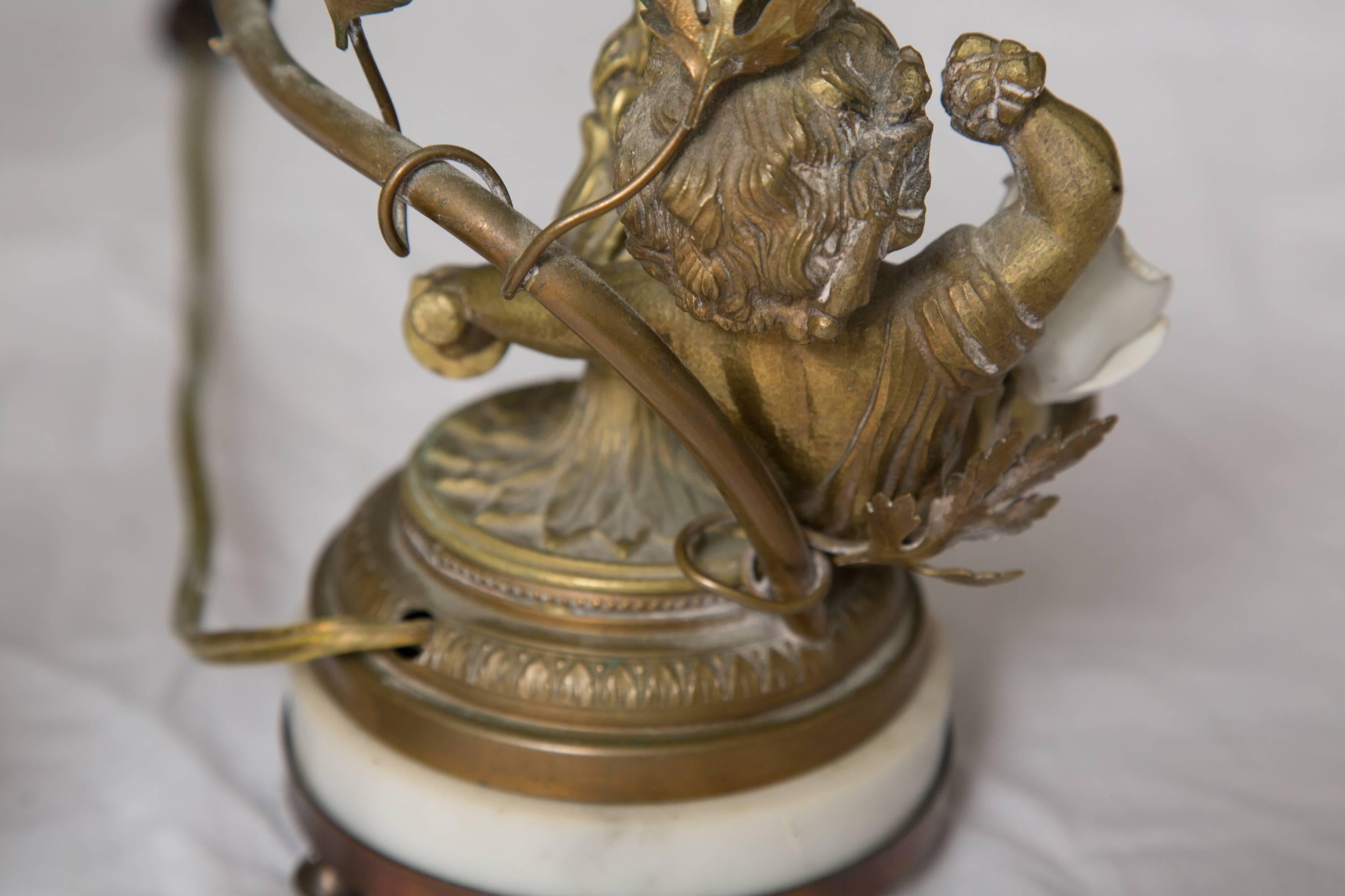 This is a pair of French bronze lamps with figures of a putti beside a flame anchoring a candle arm encrusted with porcelain rose buds. The lamps are situated on a bronze and marble circular base, circa 1880.