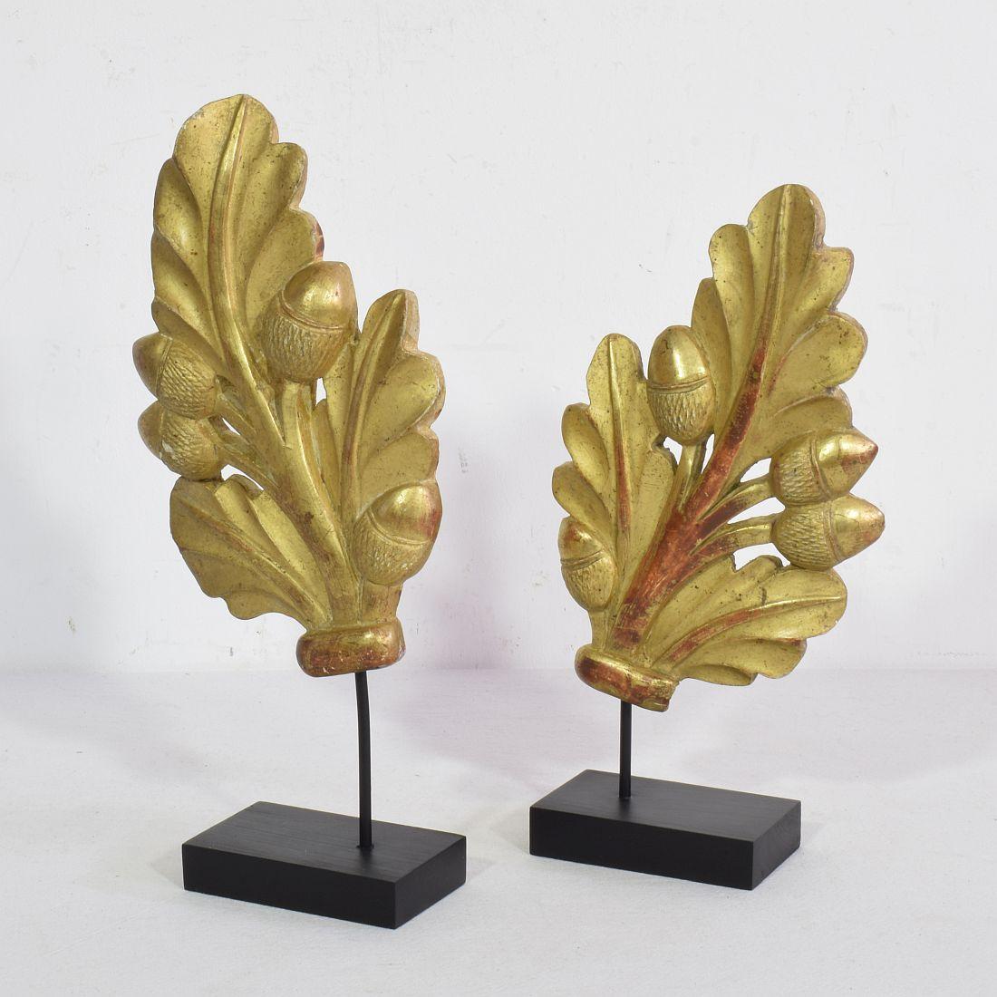 Nice couple of two giltwood neoclassical ornaments,
France, circa 1800-1850. Weathered.H:23,5-26,5cm W:12cm D:5cm 
Measurement here below includes the wooden base.