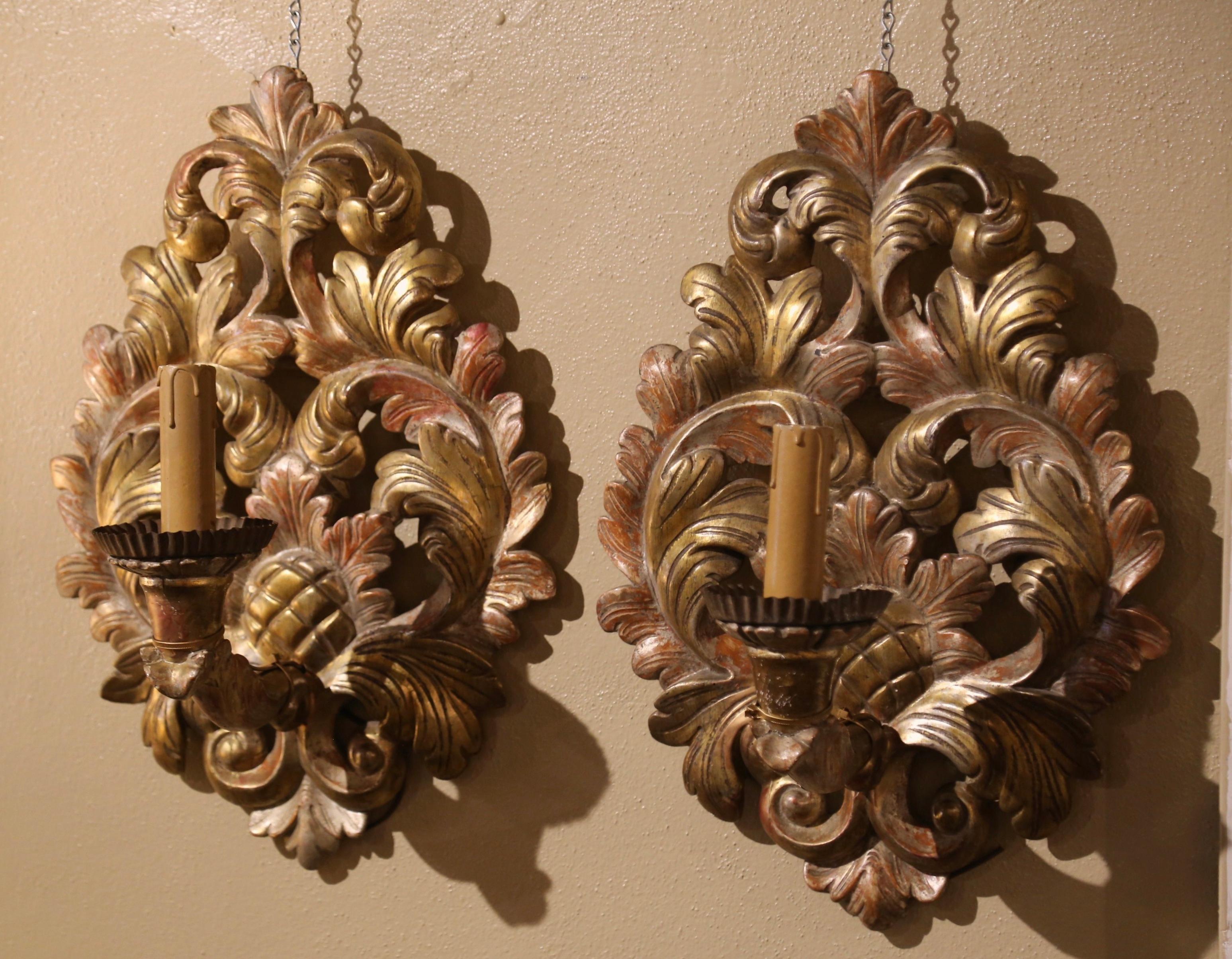 Make an elegant statement in your home with this pair of antique giltwood wall lights. Crafted in France circa 1850, and oval in shape, each large sconce features hand carved acanthus leaf decor throughout; the fixture is dressed with a single