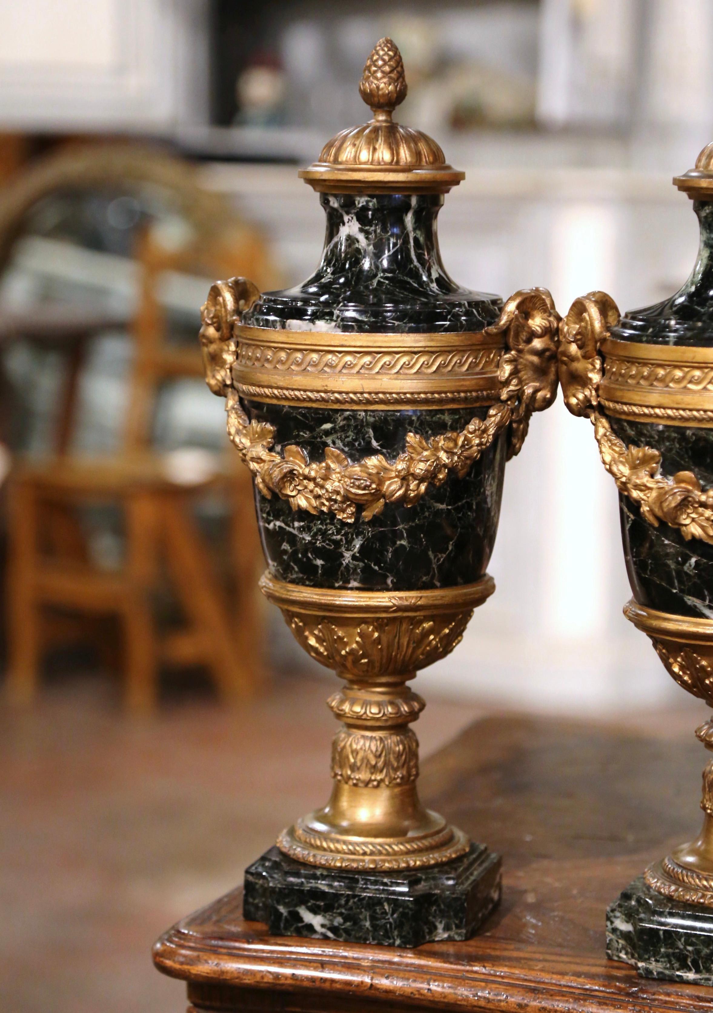 Decorate a mantel or a console with this elegant pair of antique cassolettes. Crafted in France, circa 1890, these urns stand on square marble bases with recessed corners. Each vessel built of marble is dressed with a dome shaped lid embellished