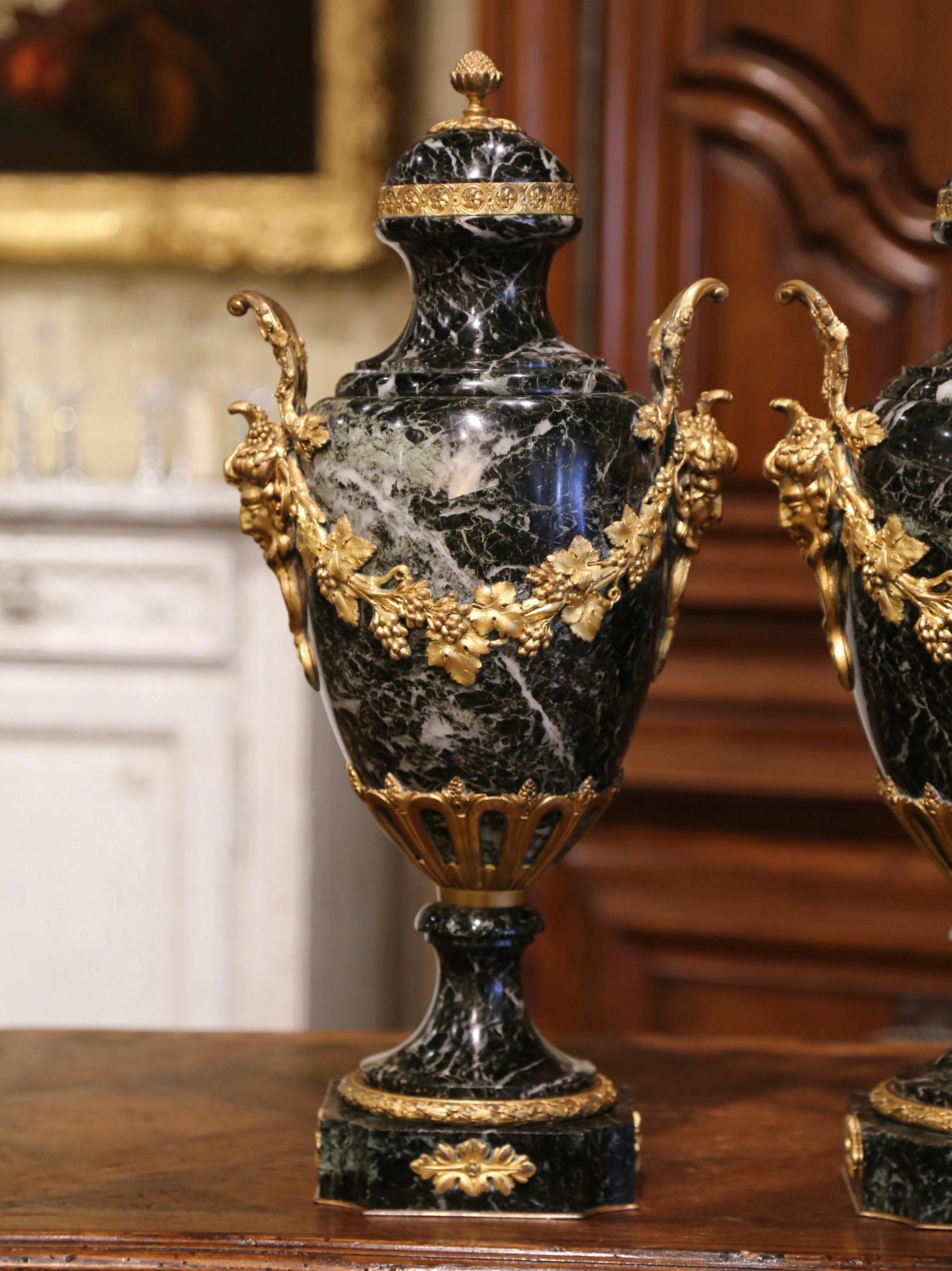Crafted in France, circa 1870, these large antique urns are carved of marble and stand on square bases with cut corners decorated with rosettes medallions on each side. Each vessel with bronze ring and foliage motifs at the base, is dressed with a