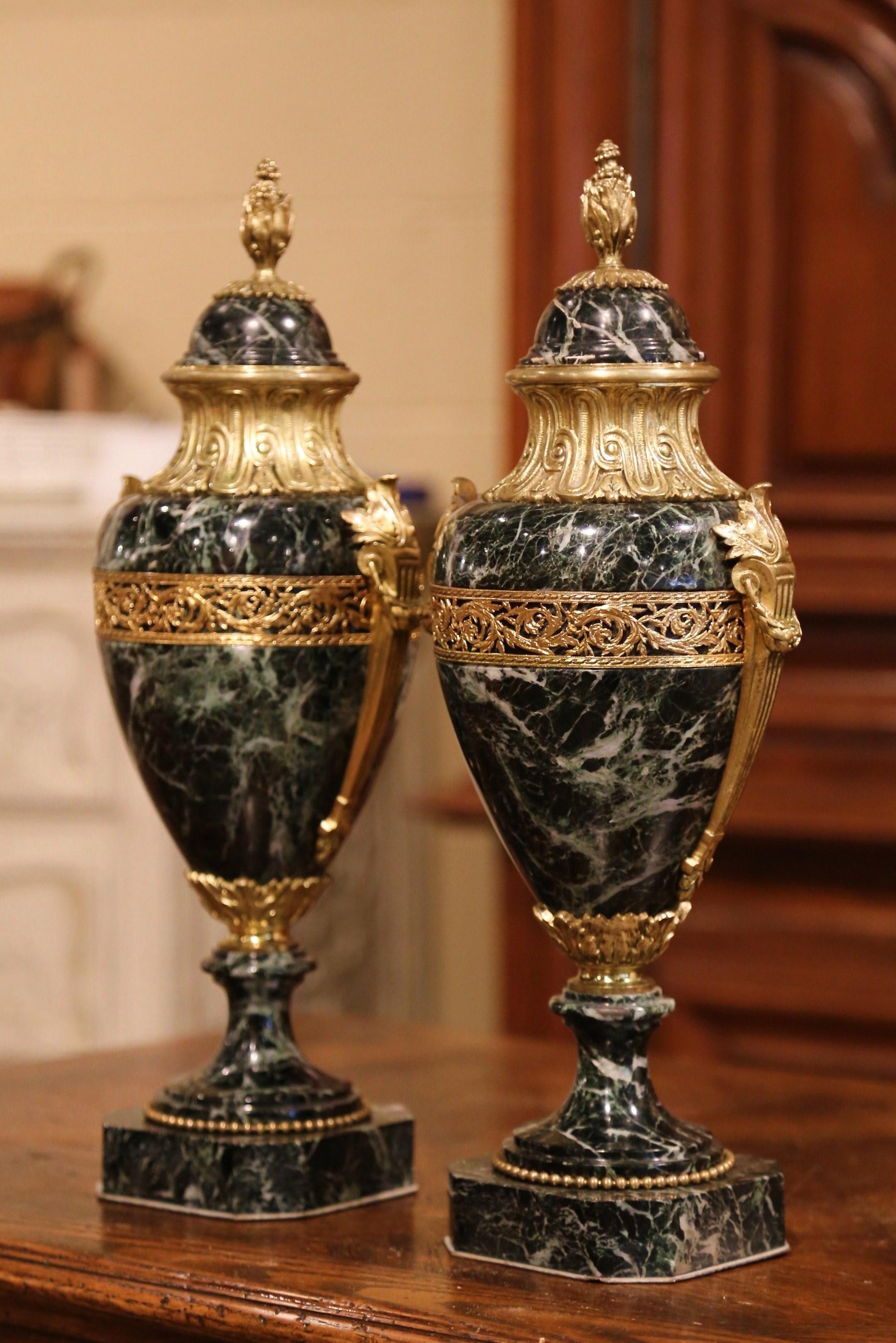 Crafted in France, circa 1870, these antique urns are carved of marble and stand on square bases with cut corners decorated with beads. Each vessel with a bronze mount around the neck, features a detachable dome shaped lid embellished with a bronze