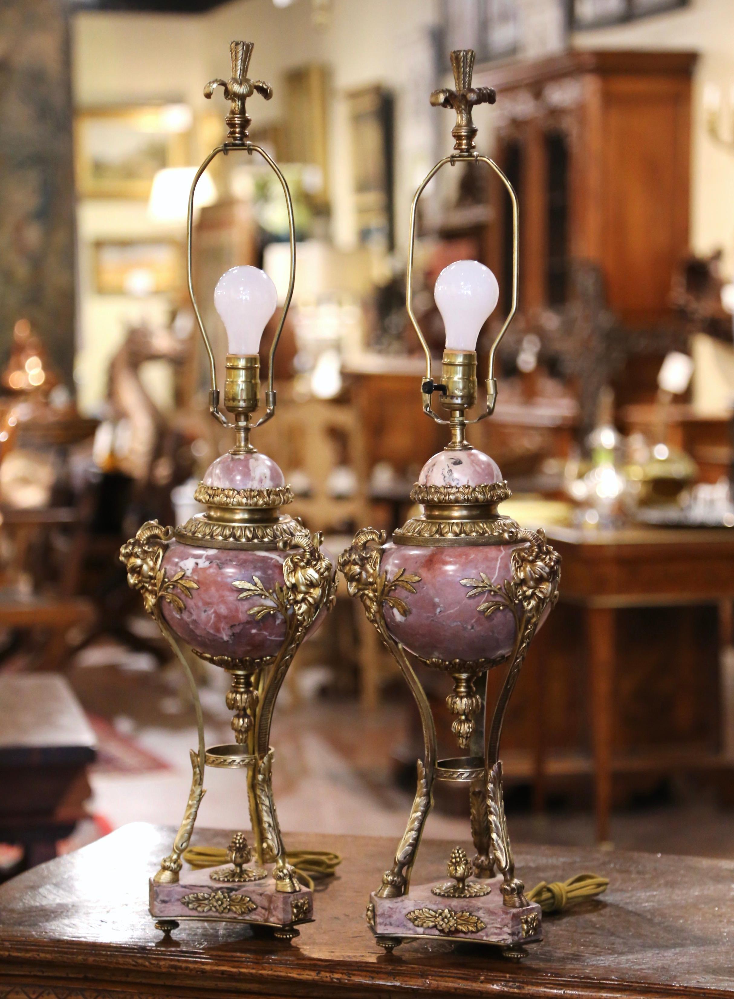 Crafted in France, circa 1870 and made of marble and bronze, these antique urns converted into table lamps stand on a three-leg bronze base ending with hoof feet, over a marble bottom and small round feet. Decorated with bronze dore gilt leaf