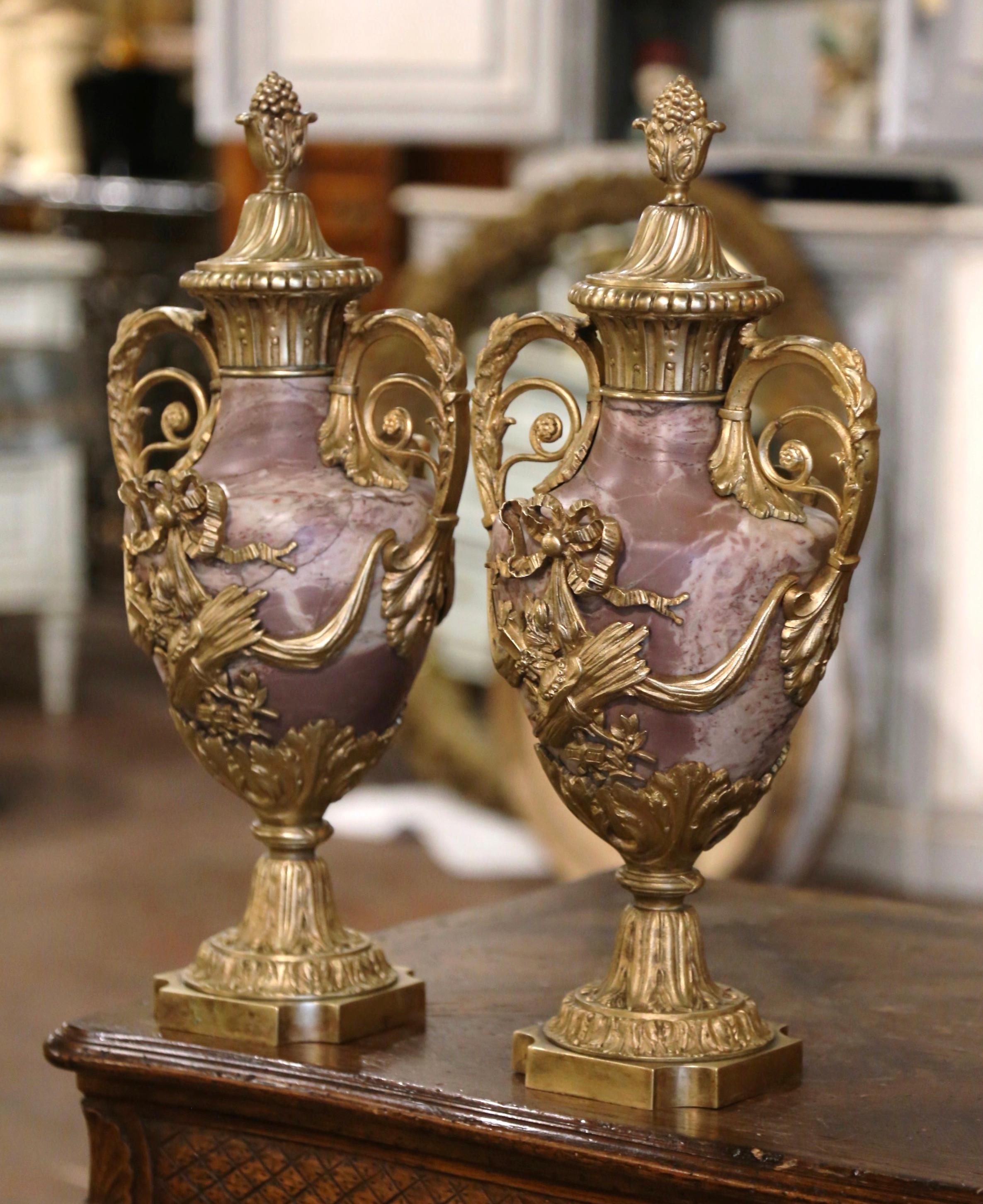 Decorate a mantel or a console with this elegant pair of antique Louis XVI cassolettes. Crafted in France, circa 1870, each urn made of marble stand on a square bronze base with cut corners decorated with acanthus leaf motifs. The marble vessel with