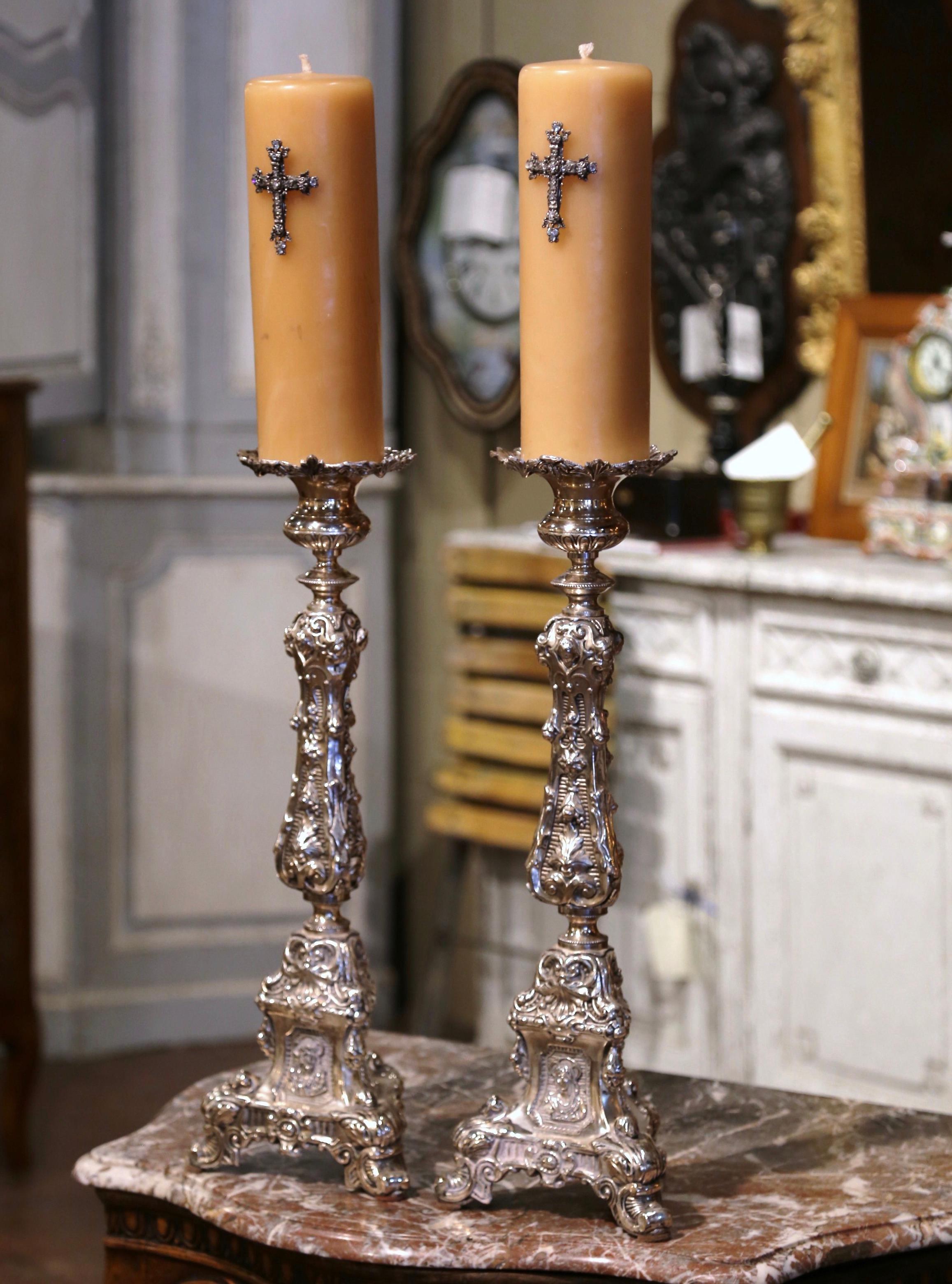 Add an air of drama and elegance to your home with this important pair of antique candlesticks with wax candles. Crafted in France circa 1870, each church candle holder stands on a sturdy triangle base decorated with acanthus leaf motifs over three