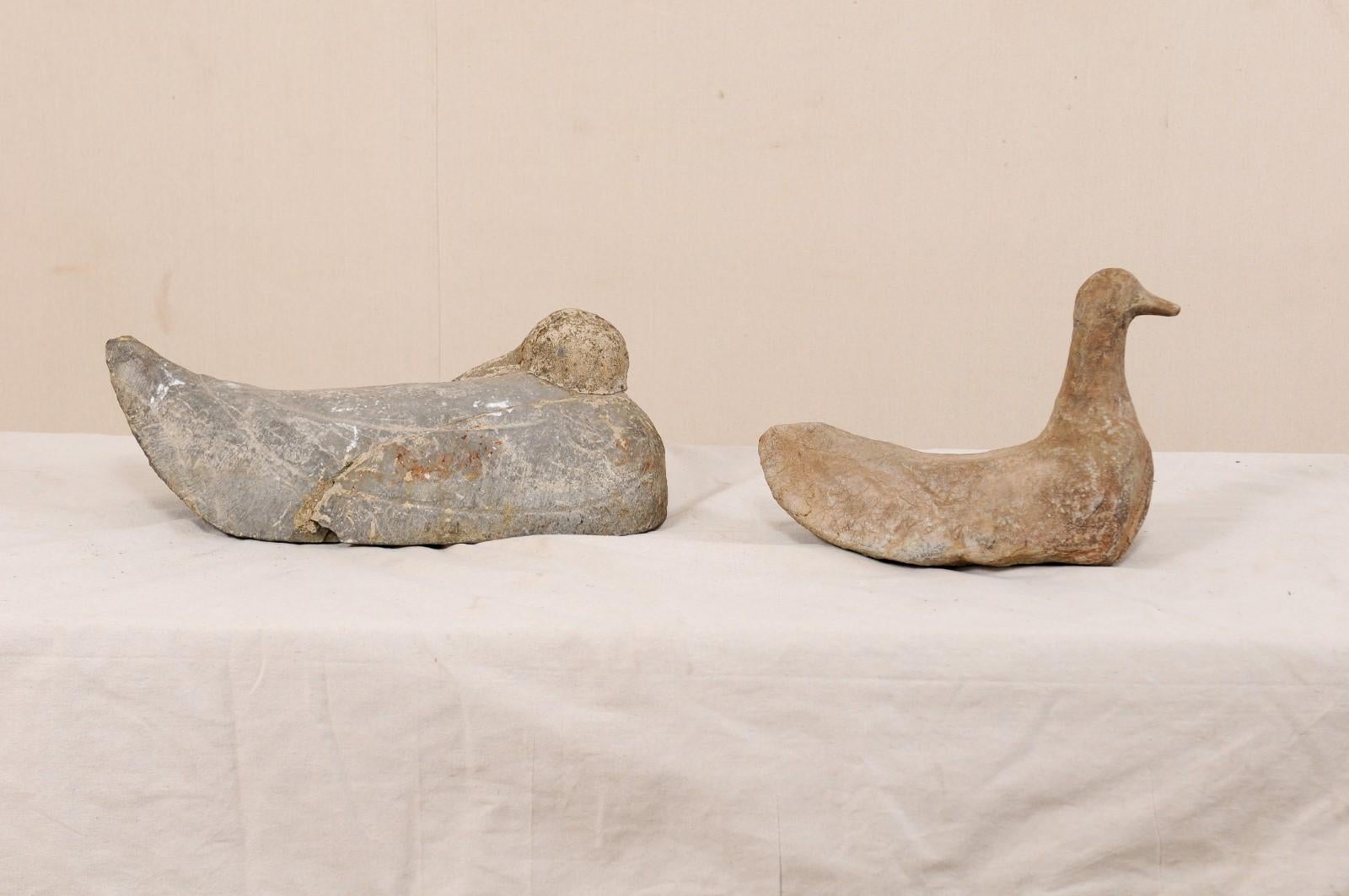 Ein Paar französische geschnitzte Steinenten aus dem 19. Jahrhundert. Dieses entzückende Paar antiker Steinenten aus Frankreich wurde in primitiver Weise handgeschnitzt und zeigt eine schlafende Ente mit nach hinten geneigtem Kopf sowie eine