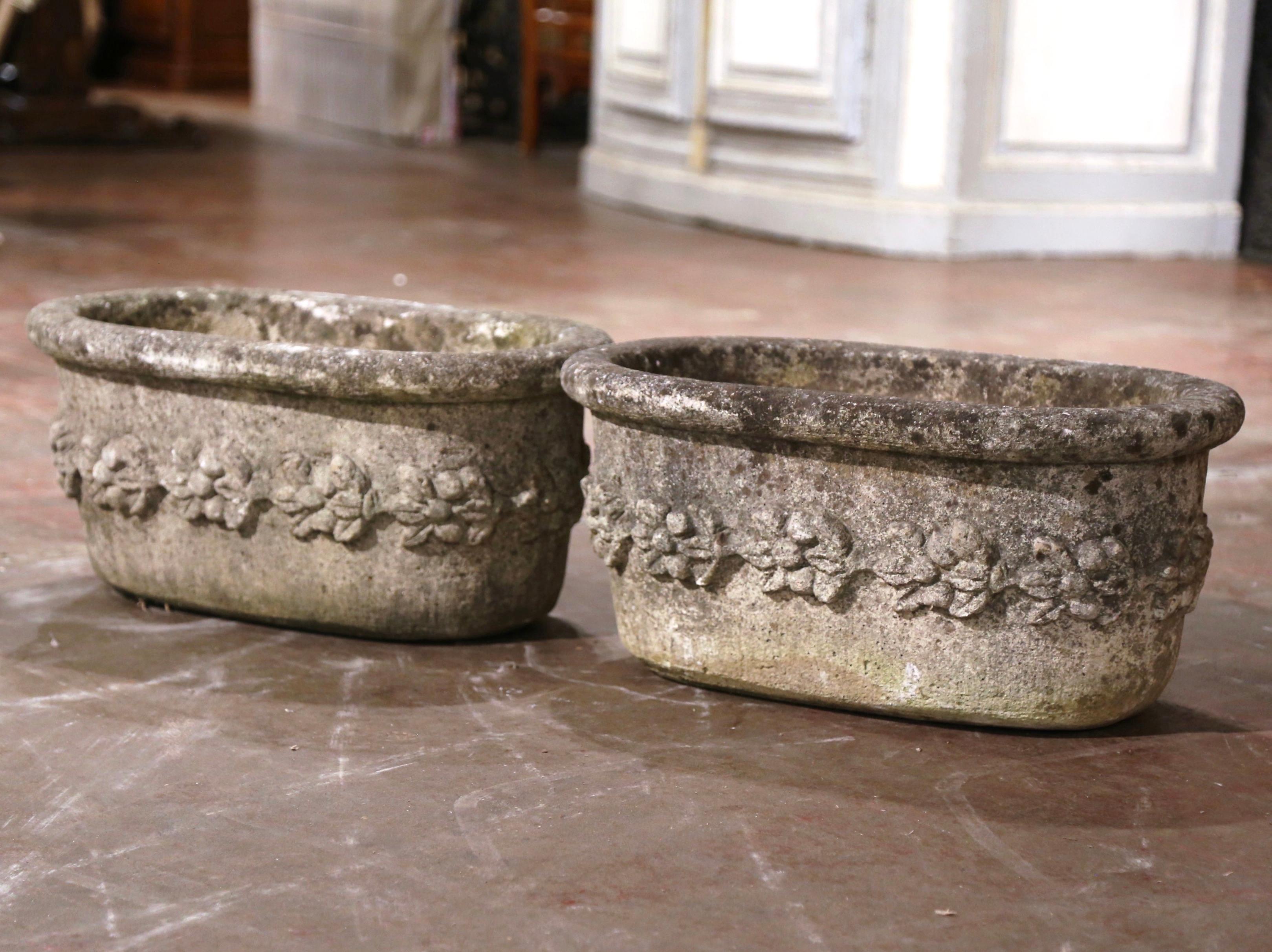 Decorate a patio with this pair of heavy antique outdoor planters. Carved in Normandy France, circa 1880, and oval in shape, each  jardinière with drainage holes in the bottom, is decorated with hand-carved high relief bunch of floral and leaf decor