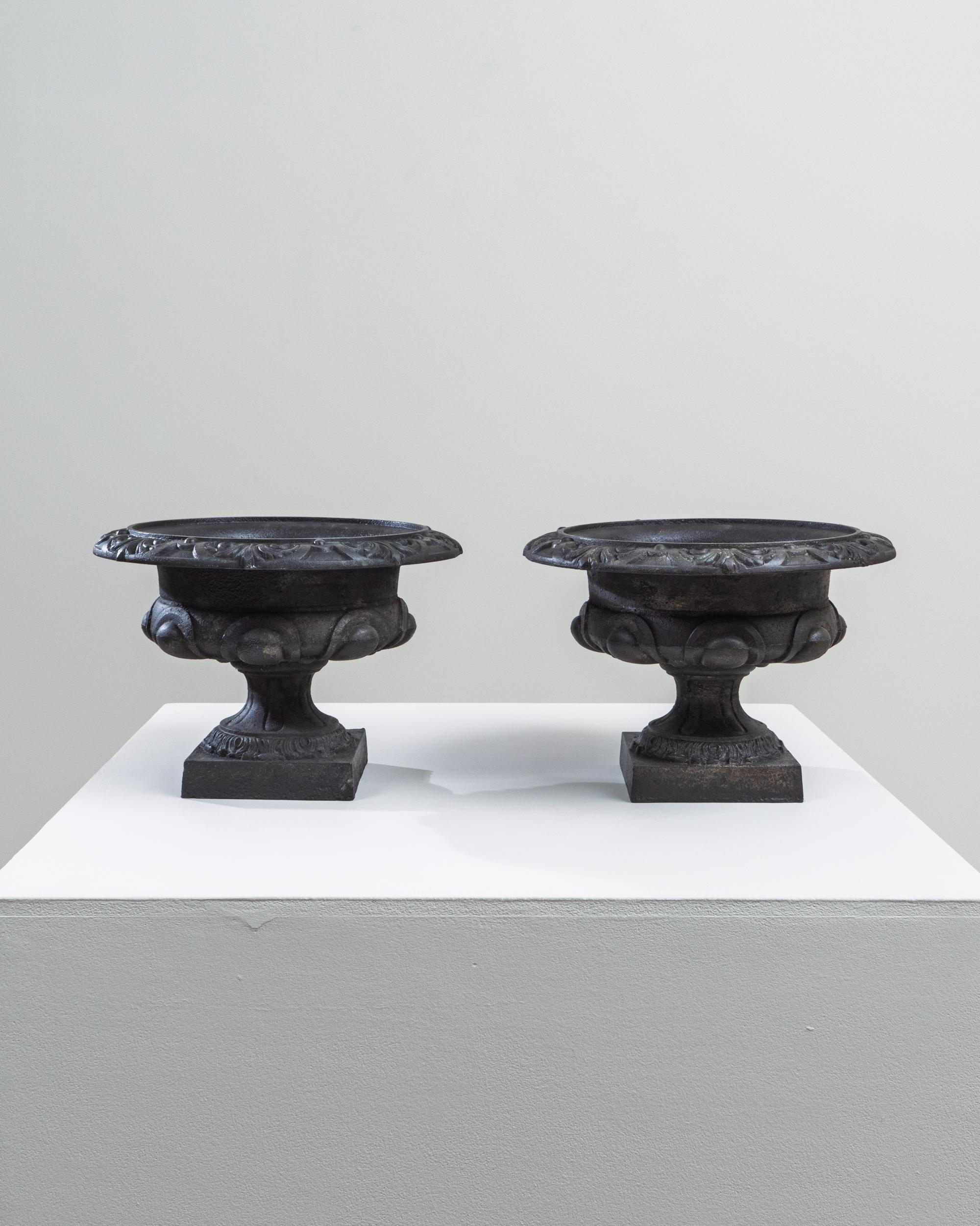 Pair of 19th Century French Cast Iron Planters. This elegant pair of French cast iron planters from the 19th century showcases the refined detailing and enduring craftsmanship typical of the period. Each planter rests on a square plinth base