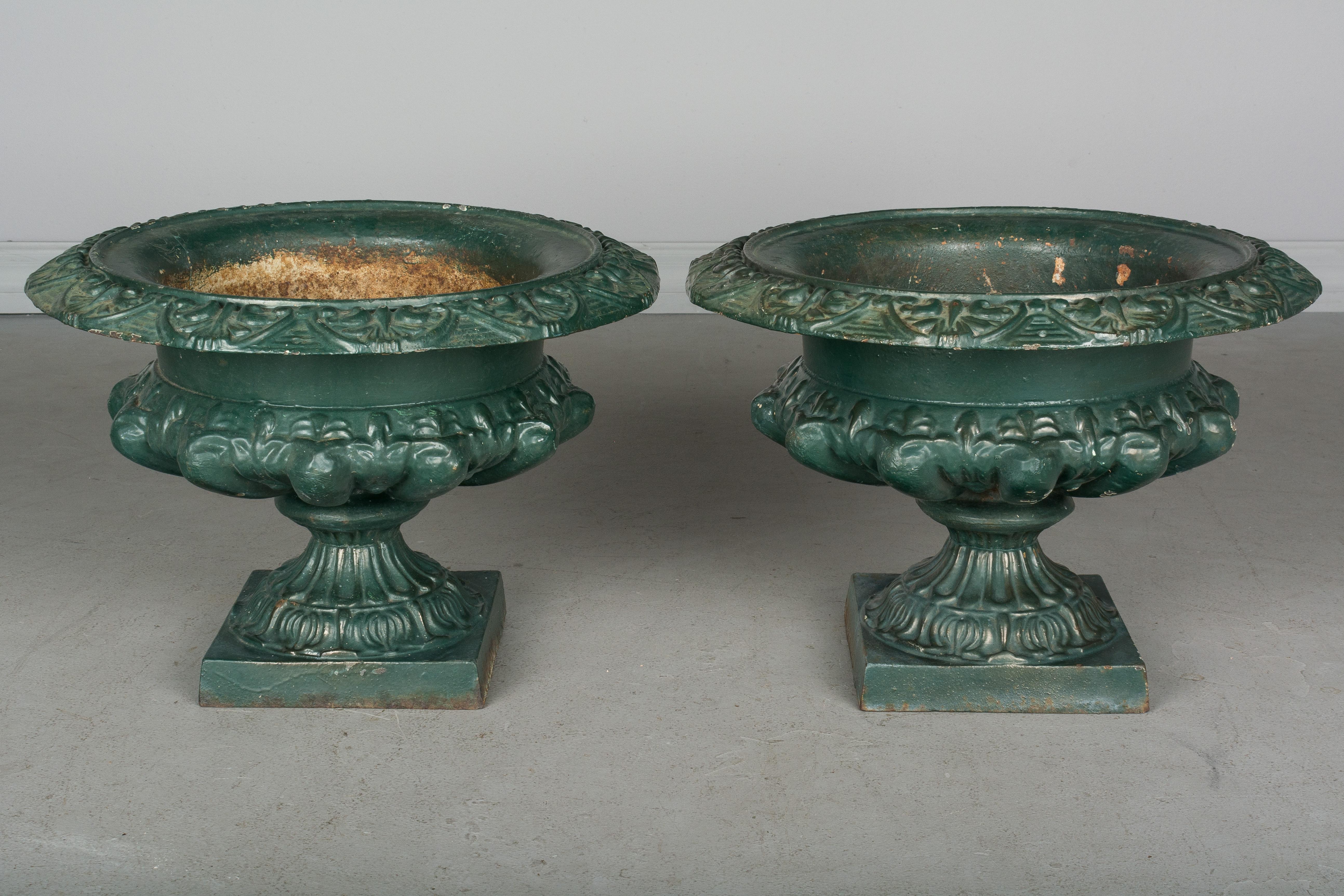 A pair of 19th century French cast iron garden urn planters, with original weathered green painted patina. Weight: 40 lbs. each. 11.5