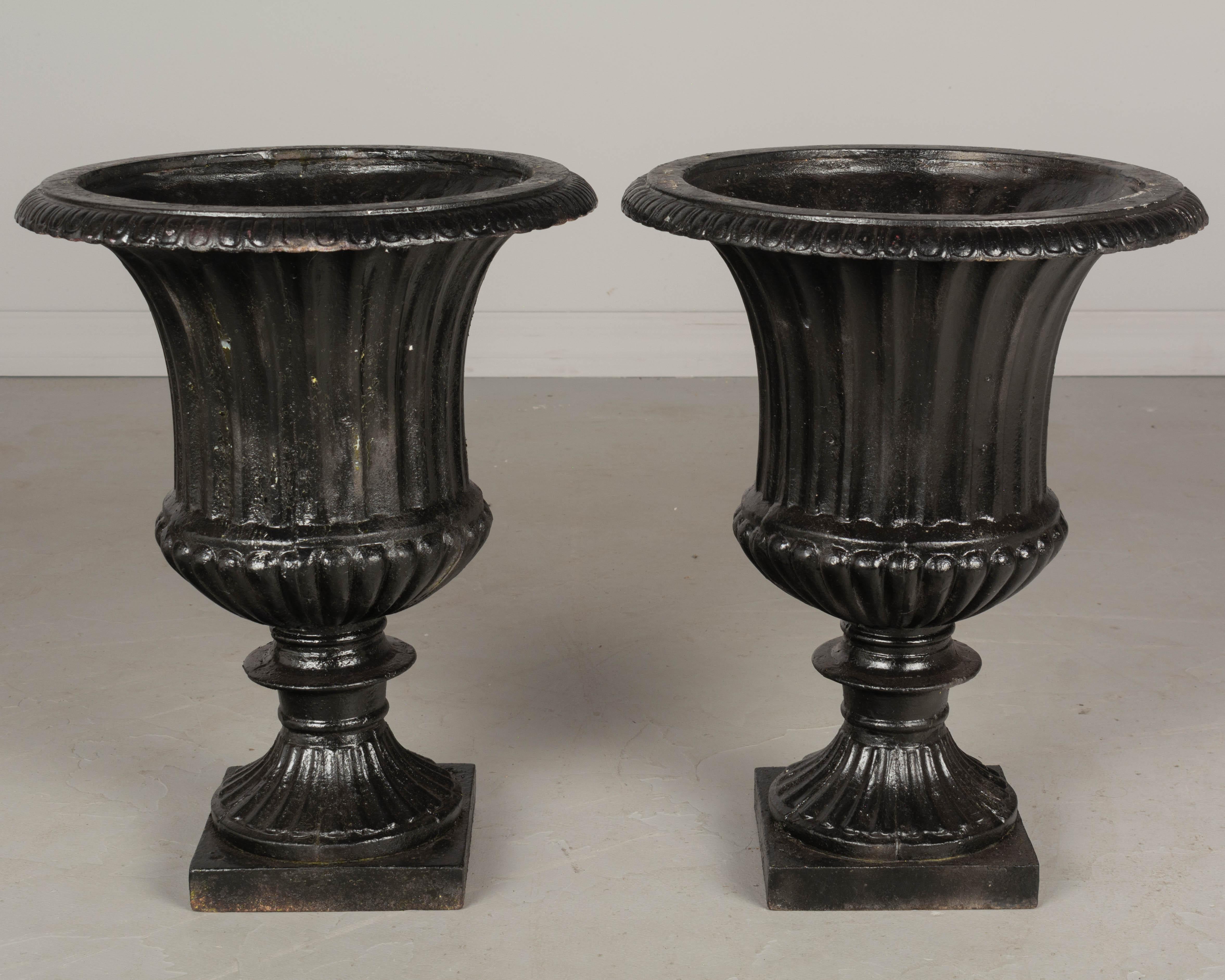 A pair of 19th century French cast iron Medicis garden urn planters with black painted patina. Tall proportions with flared fluted form and pedestal base. Circa 1870-1880. 
Weight: 37.6 lbs. each
19