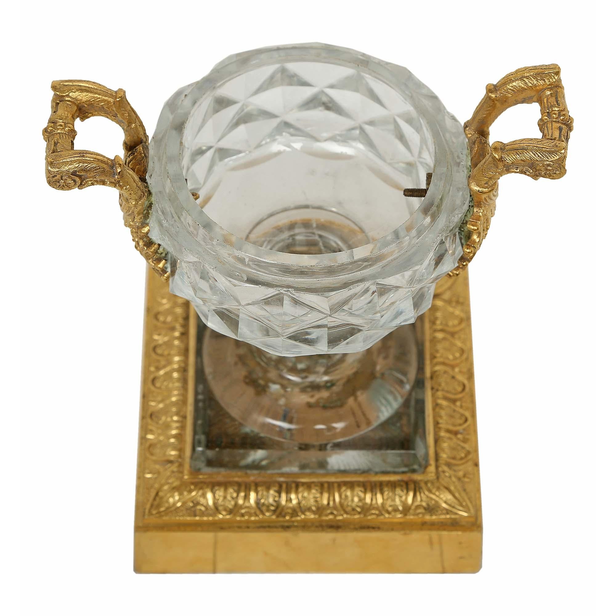 Une paire exquise de tazza en cristal de Baccarat et bronze doré du 19ème siècle. Chaque tazza en cristal de Baccarat repose sur une base carrée en bronze doré avec une bordure en forme de feuille d'acanthe. Les urnes en cristal merveilleusement