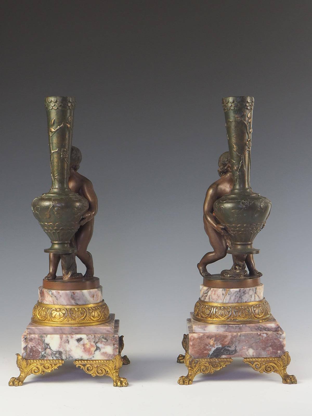 Una squisita coppia di putti francesi in stile Art Nouveau della fine del XIX secolo, dorati e patinati, che mostrano l'intricata maestria dell'epoca. I cherubini, rivolti verso l'interno, reggono un lungo vaso a collo di bottiglia ornato da un