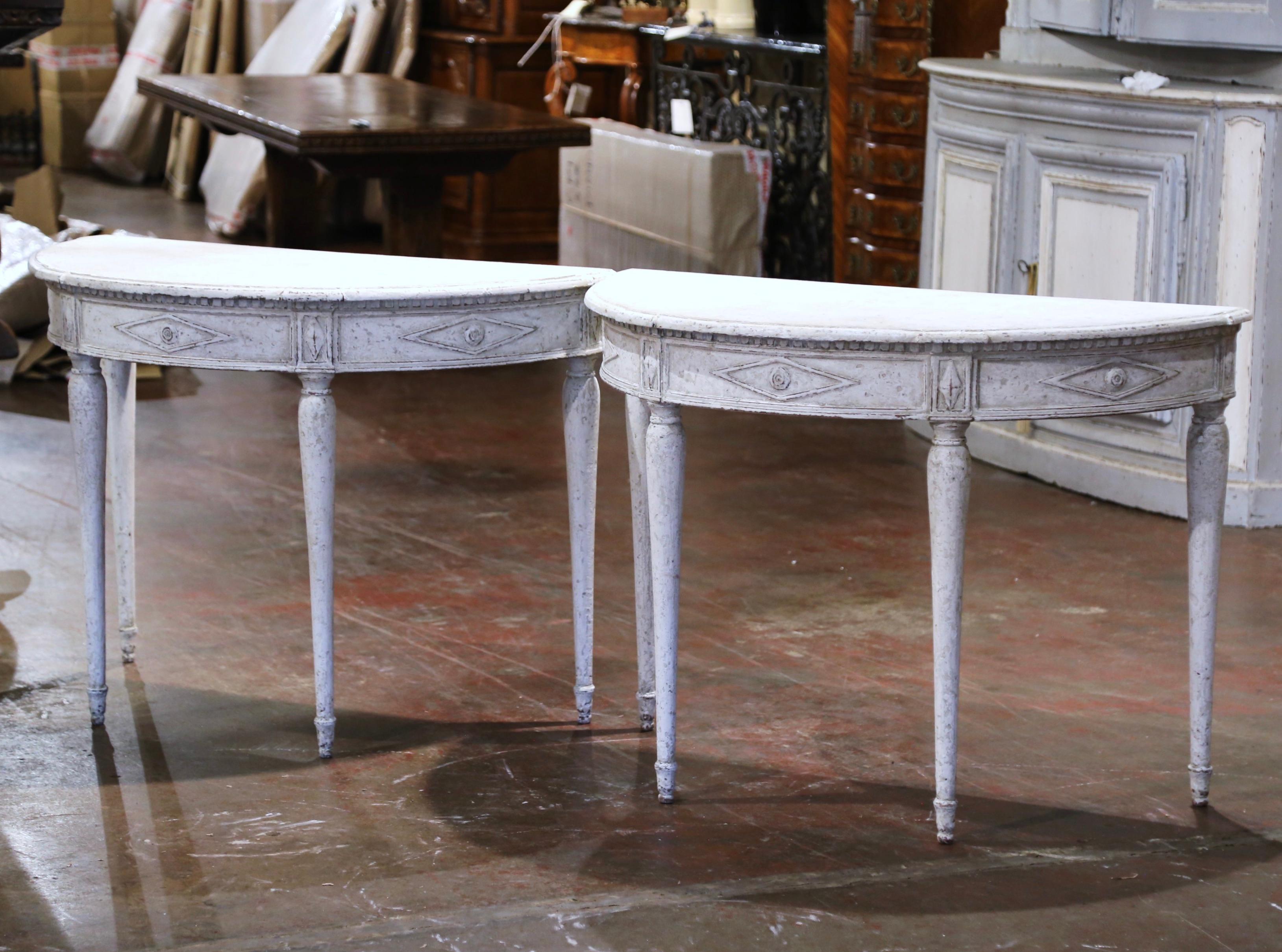 Decorate an entryway with this elegant pair of antique painted consoles. Crafted in northern France, circa 1880 and shaped as half moon, each style table stands on four tapered and rounded legs decorated with diamond shape rosettes at the shoulders;