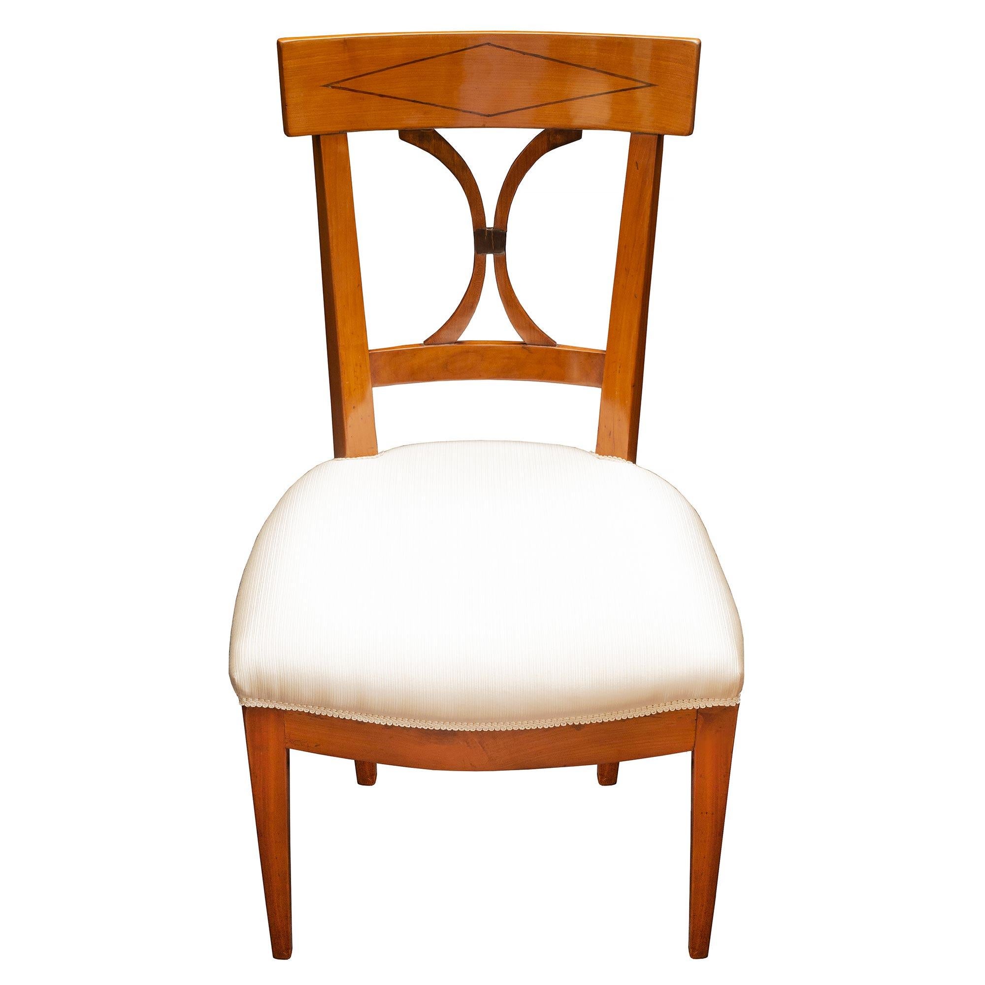 An elegant and unusual pair of 19th century, French Directoire st. cherry wood chair. The chairs are raised by slightly curved legs below a stunning straight apron with an attractive curved shape at the front. The pierced back has a most elegant