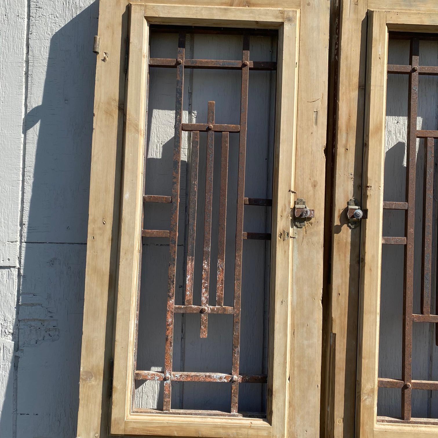 Pair of stunning stripped 19th century French doors with wrought iron, featuring bold molded detail framing the lower panels as well as the intricate wrought iron inserts, which open, above, which are artfully wrought in a beautiful geometric