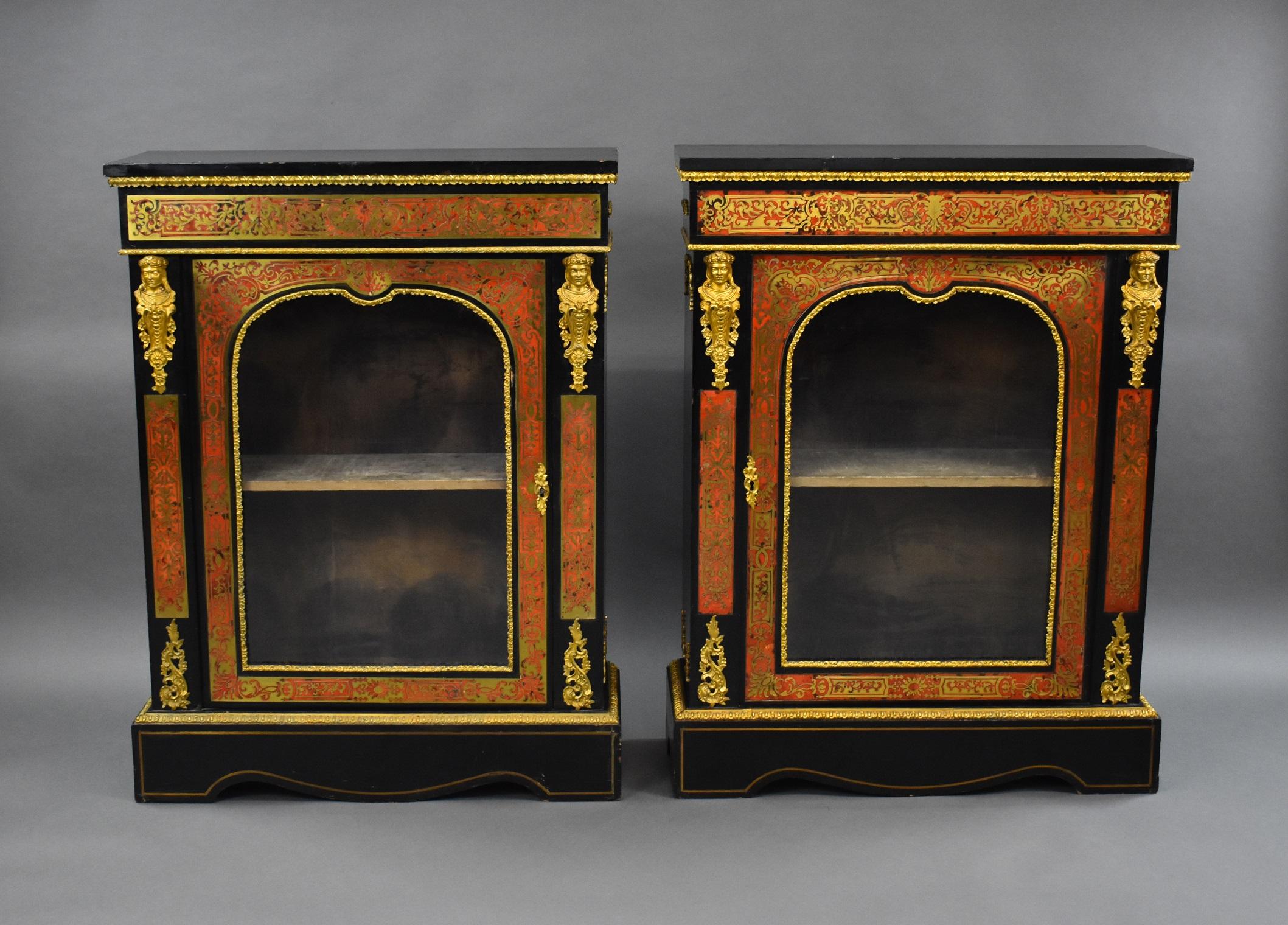 For sale is a good quality pair of ebonised Boulle pier cabinets, each with a rectangular top above a deep frieze and an arched glazed door flanked by masks above a plinth base. Both cabinets are in good condition, showing minor signs of wear