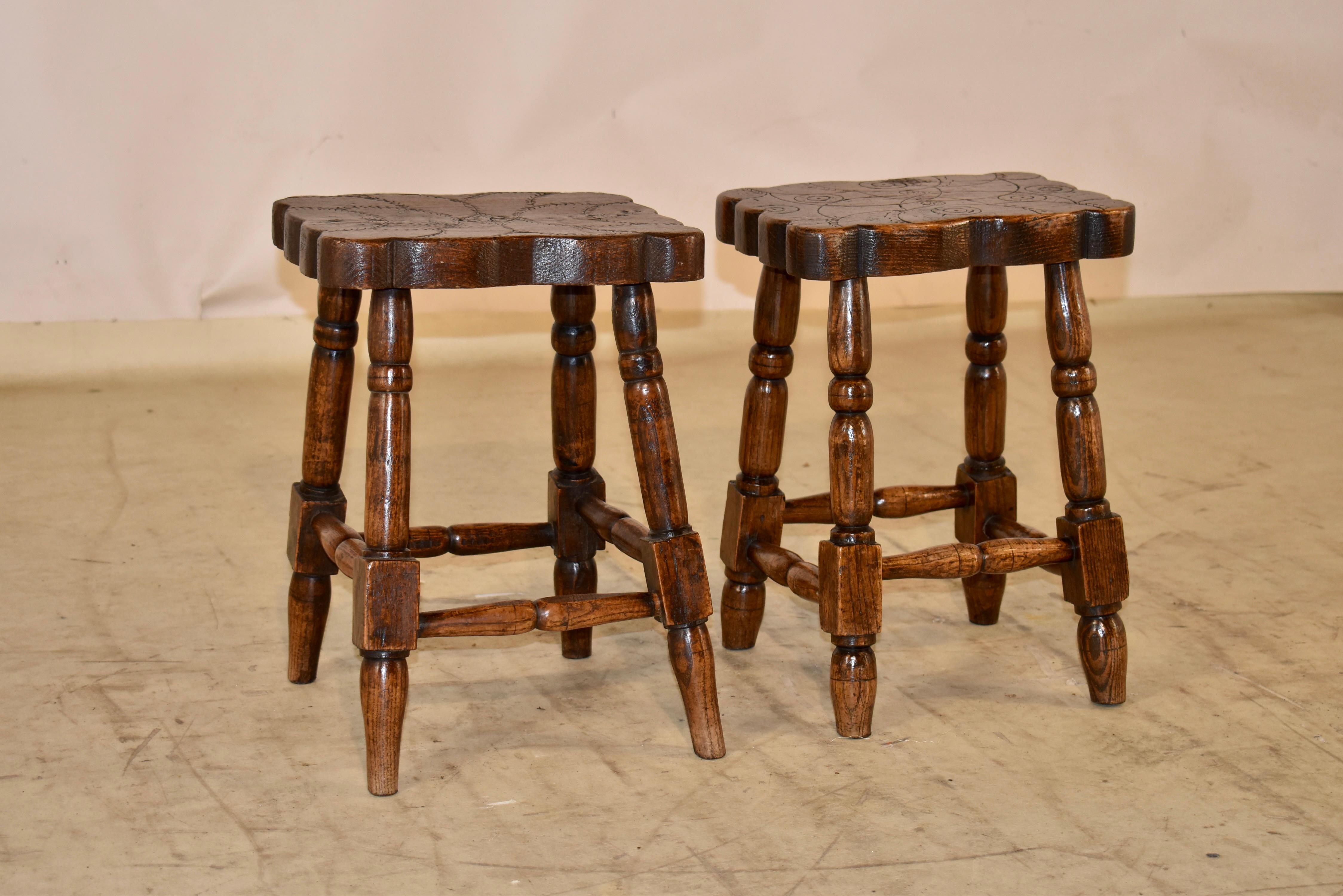 Coppia di incantevoli sgabelli in olmo dell'inizio del XIX secolo provenienti dalla Francia.  I piani sono costituiti da tavole di olmo tagliate spesso e presentano bordi smerlati e decorazioni intagliate a mano sui piani.  Sono sostenuti da gambe