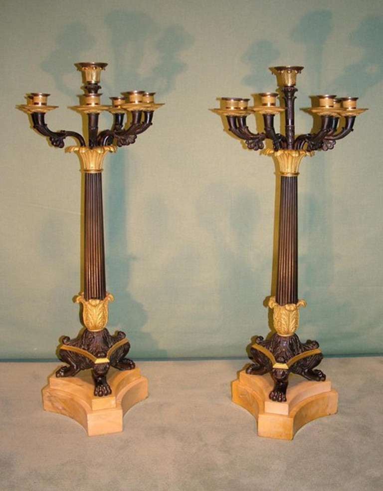 An important pair of early 19th century French Empire period seven-light bronze and Ormolu candelabras raised on fluted columns and supported on tripartite feet ending on double Sienna marble platform bases.