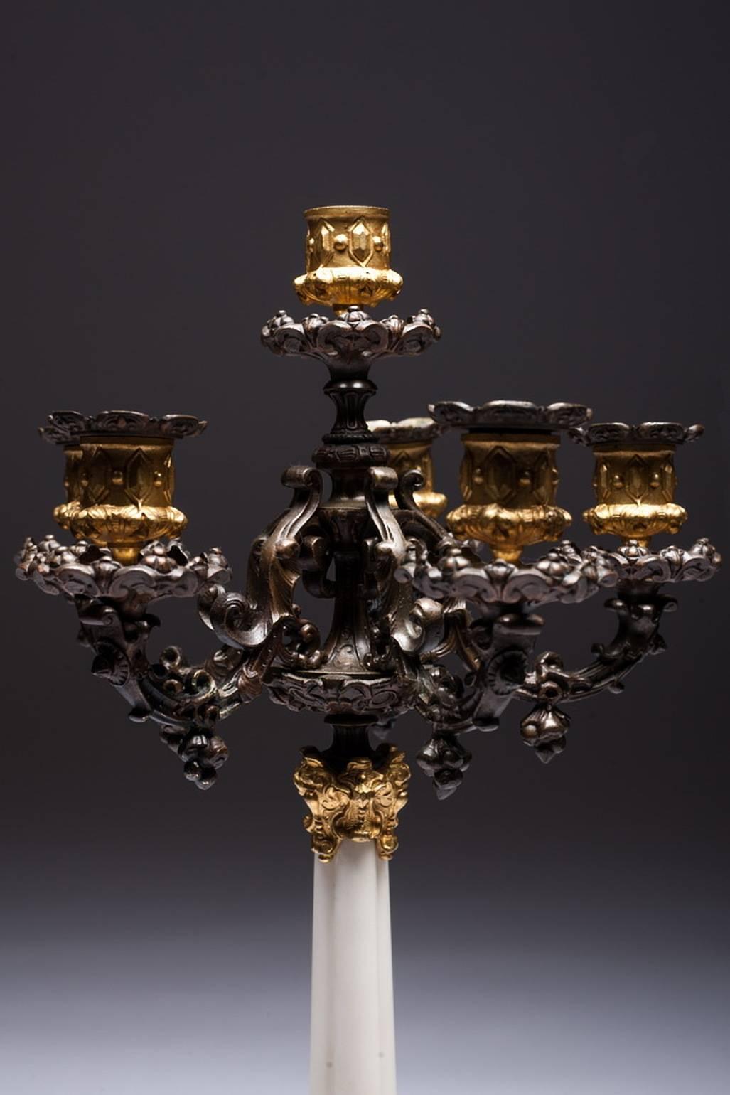 Incredible and rare pair of empire style candelabra of gilt and patinated bronze, central column is made of white marble. Place for six candles in the candelabra. Very well crafted and intricately detailed. Three cherubs are surrounded by a