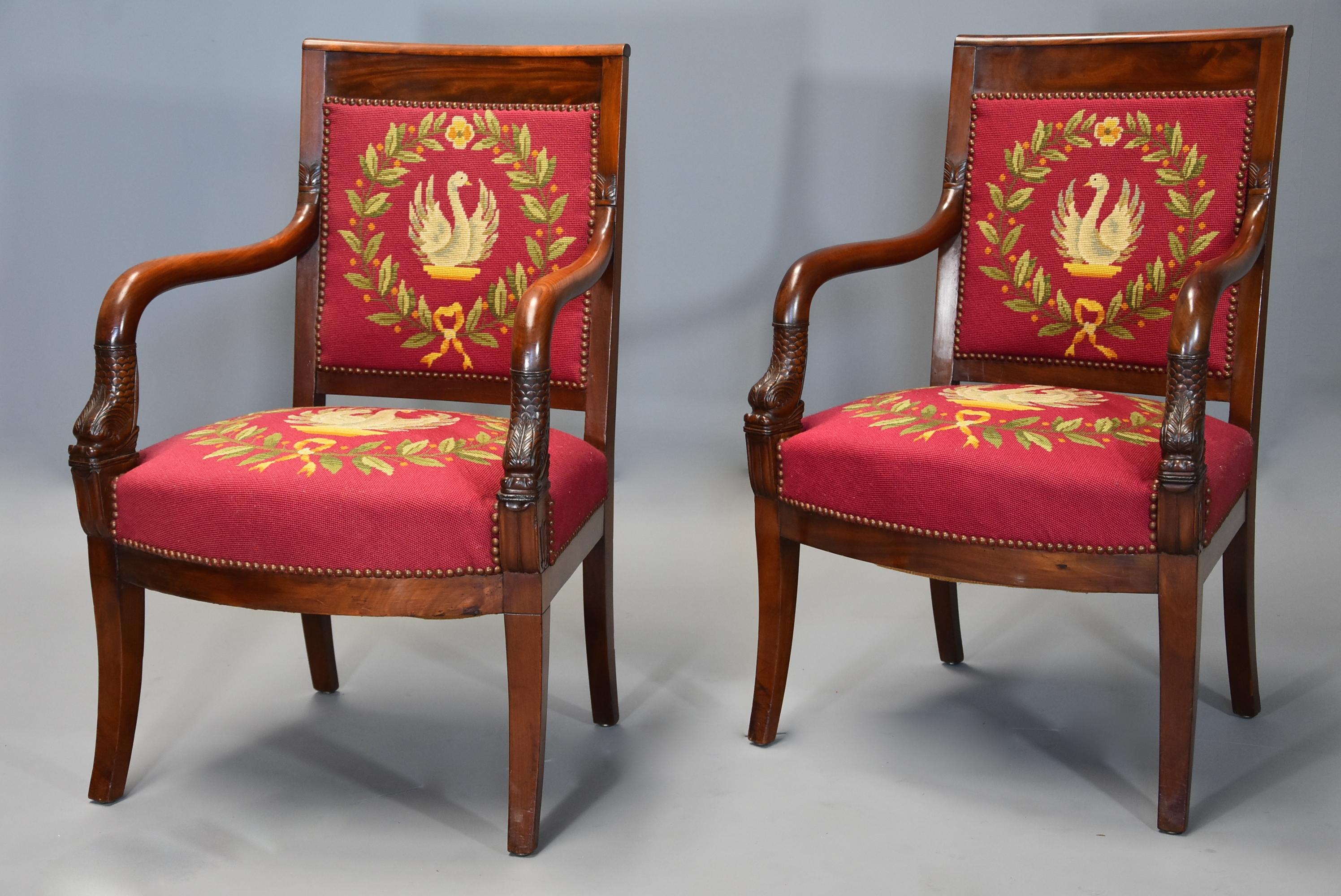 A pair of 19th century (circa 1830) French Empire mahogany fauteuils (open armchairs) of good quality with wool work upholstery of Napoleonic symbols.

This pair of chairs consist of a top rail leading down to shaped arms with carved foliate