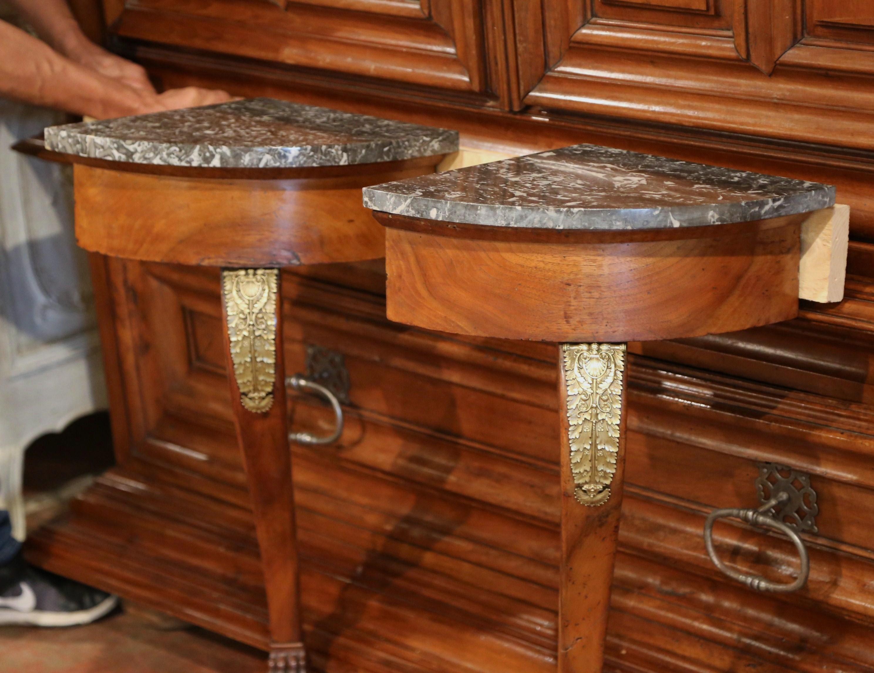 Decorate due piccoli angoli con questa coppia di consolle antiche, realizzate in Francia, intorno al 1820; ogni tavolo alto in legno di frutto poggia su un'unica gamba cabriole intagliata ed elegante, impreziosita da una montatura in bronzo a