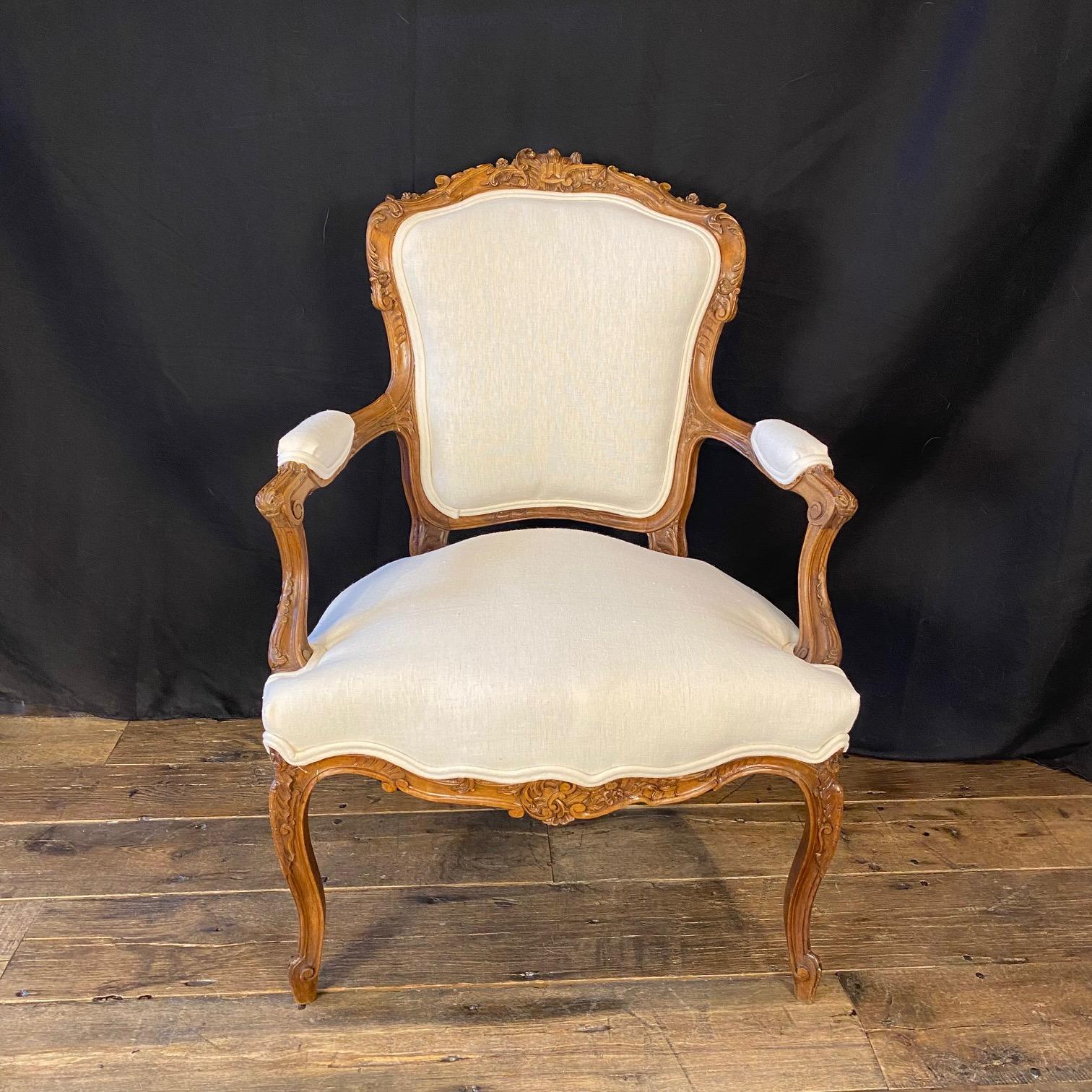 Museum quality carving on this pair of exquisite French Louis XV armchairs, accent chairs, or dining chairs, newly reupholstered in a fine high quality linen blend neutral British fabric! Please view a close up of the carving in our photos. Will add