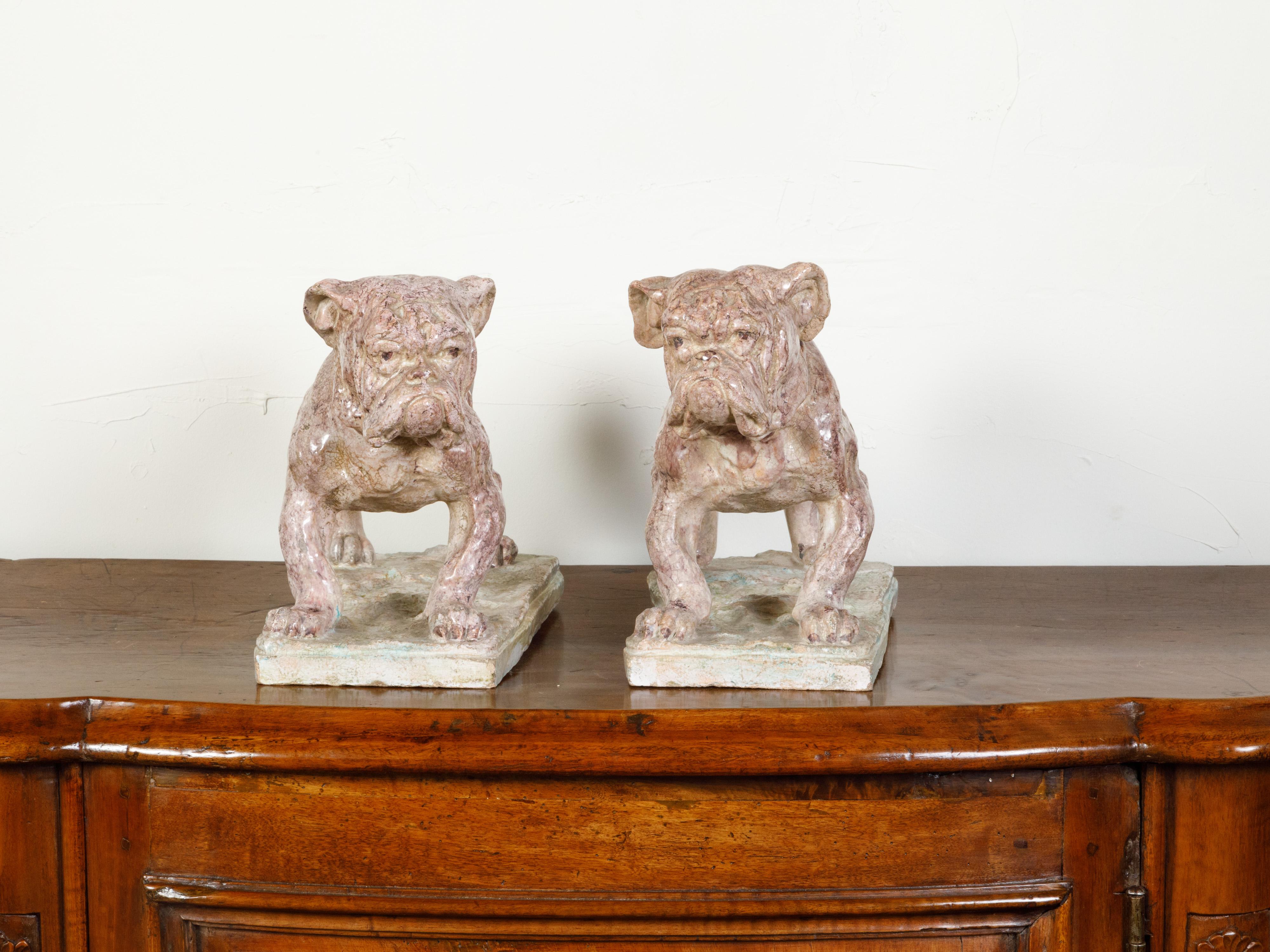 A pair of French faience bulldogs from the 19th century, on rectangular terracotta bases. Created in France during the 19th century, each of this pair of animal sculptures features a bulldog standing firmly on his four legs. Boasting a serious